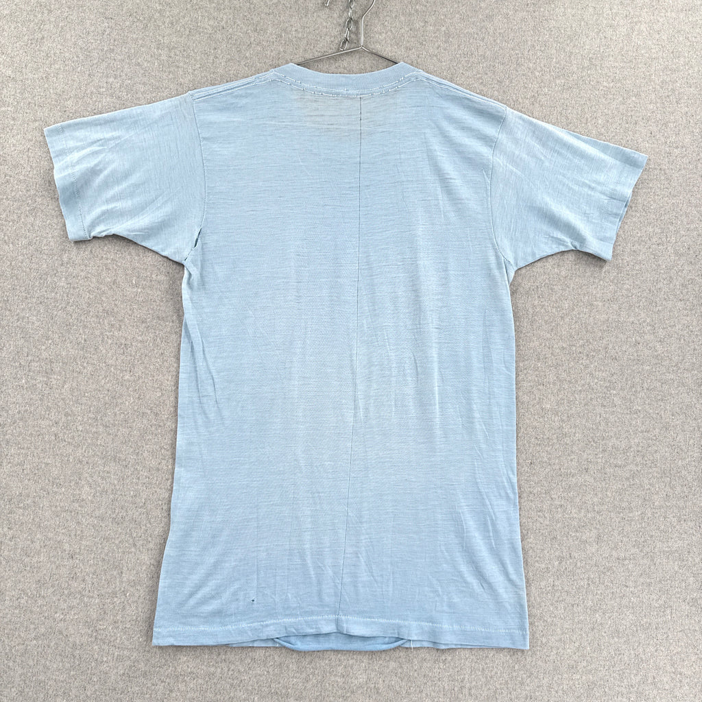 Light blue t-shirt on a hanger against a beige wall