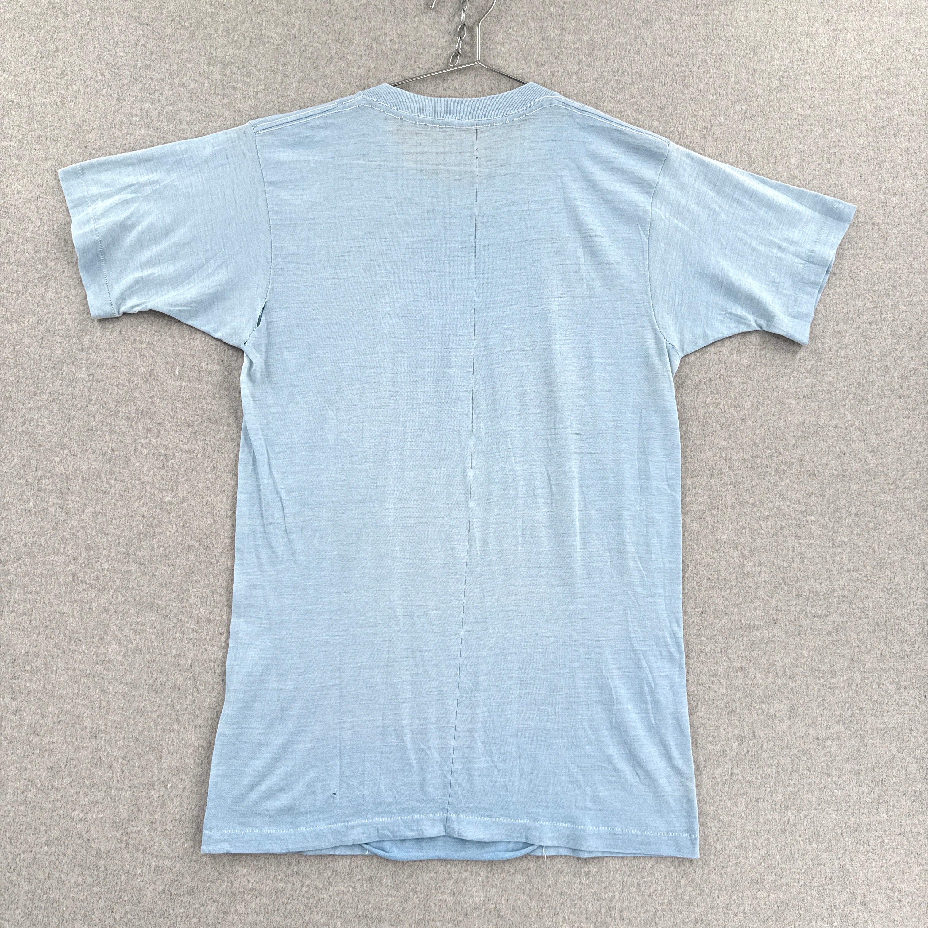 Light blue t-shirt on a hanger against a beige wall