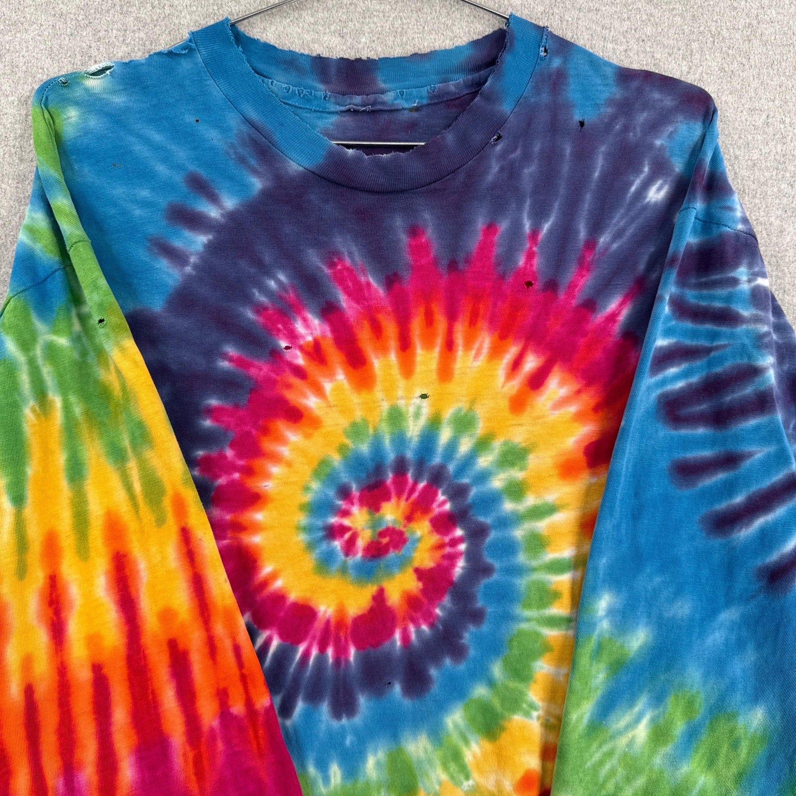 Colorful tie-dye long-sleeve shirt with a spiral pattern on a neutral background