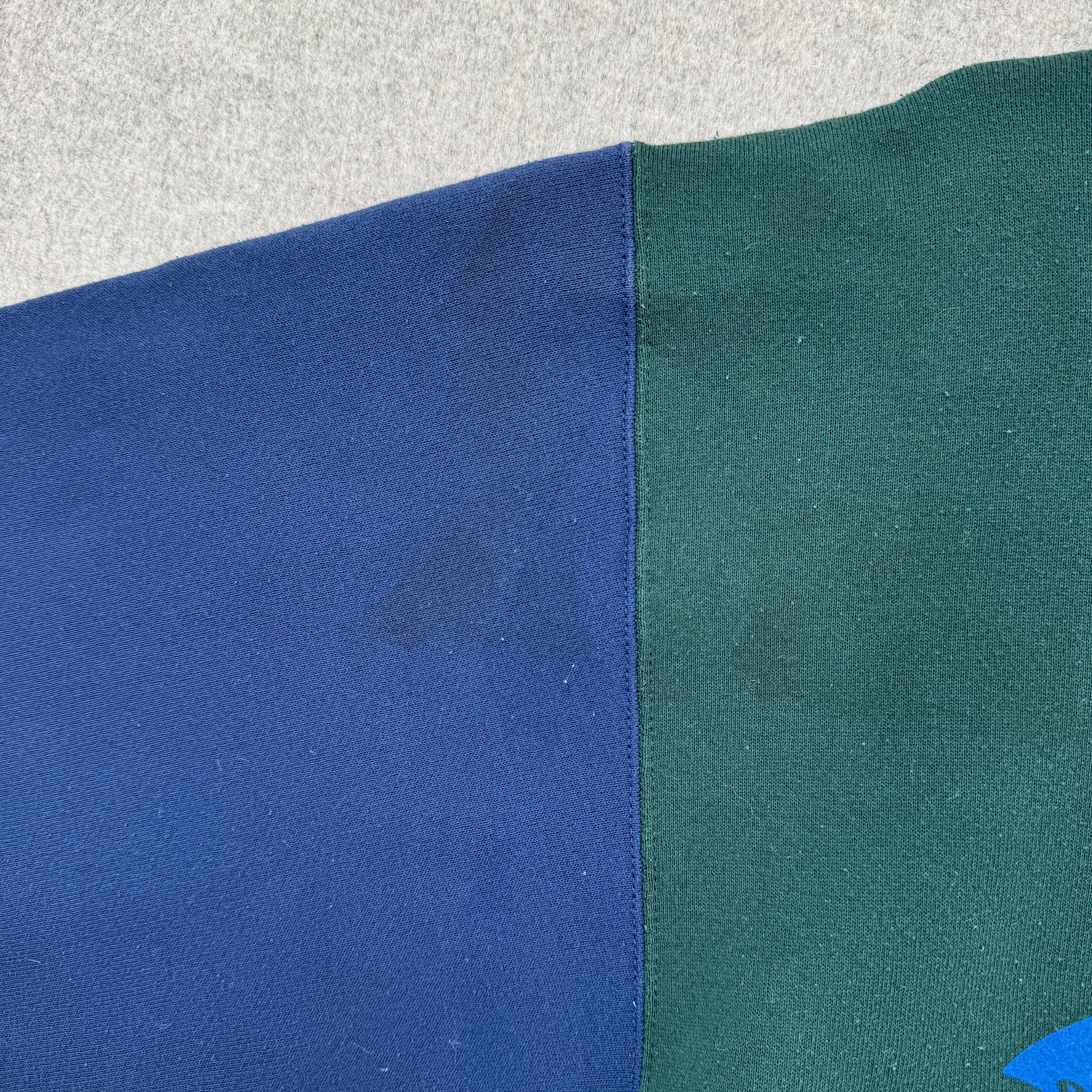 Close-up of blue and green fabric with a some dark stain spots near shoulder