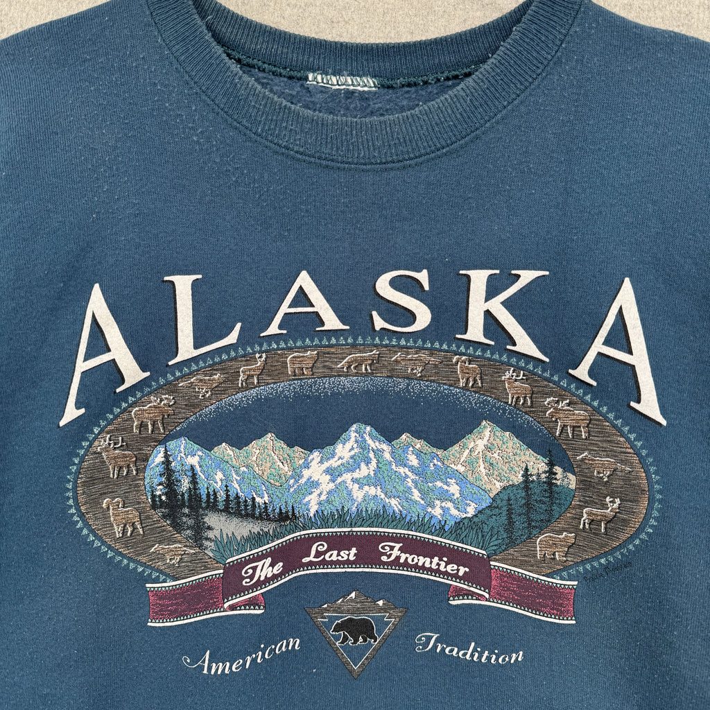 Blue sweatshirt with 'Alaska The Last Frontier American Tradition' graphic design. Mountains and animals