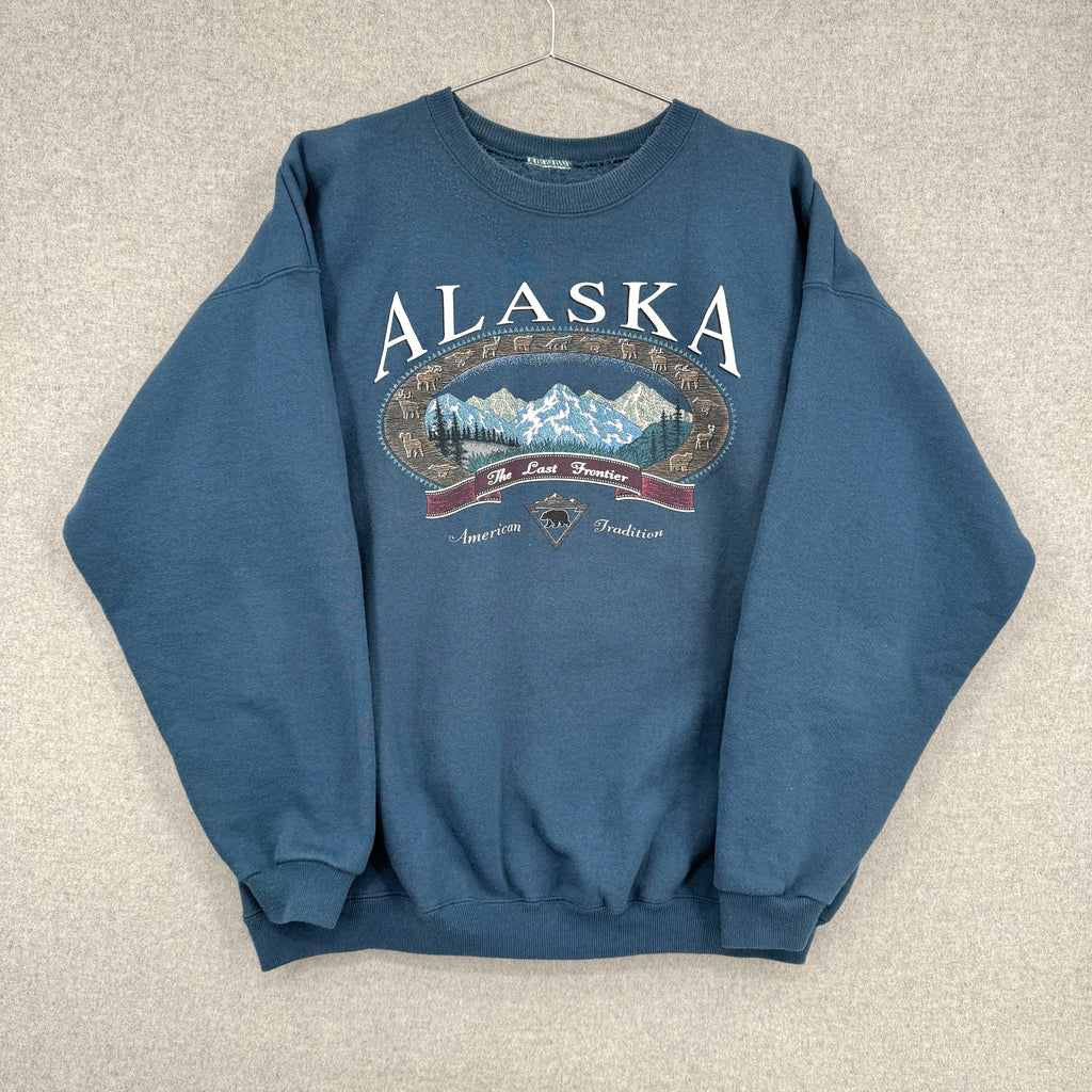 Blue sweatshirt with 'Alaska' and mountain graphic on a beige background