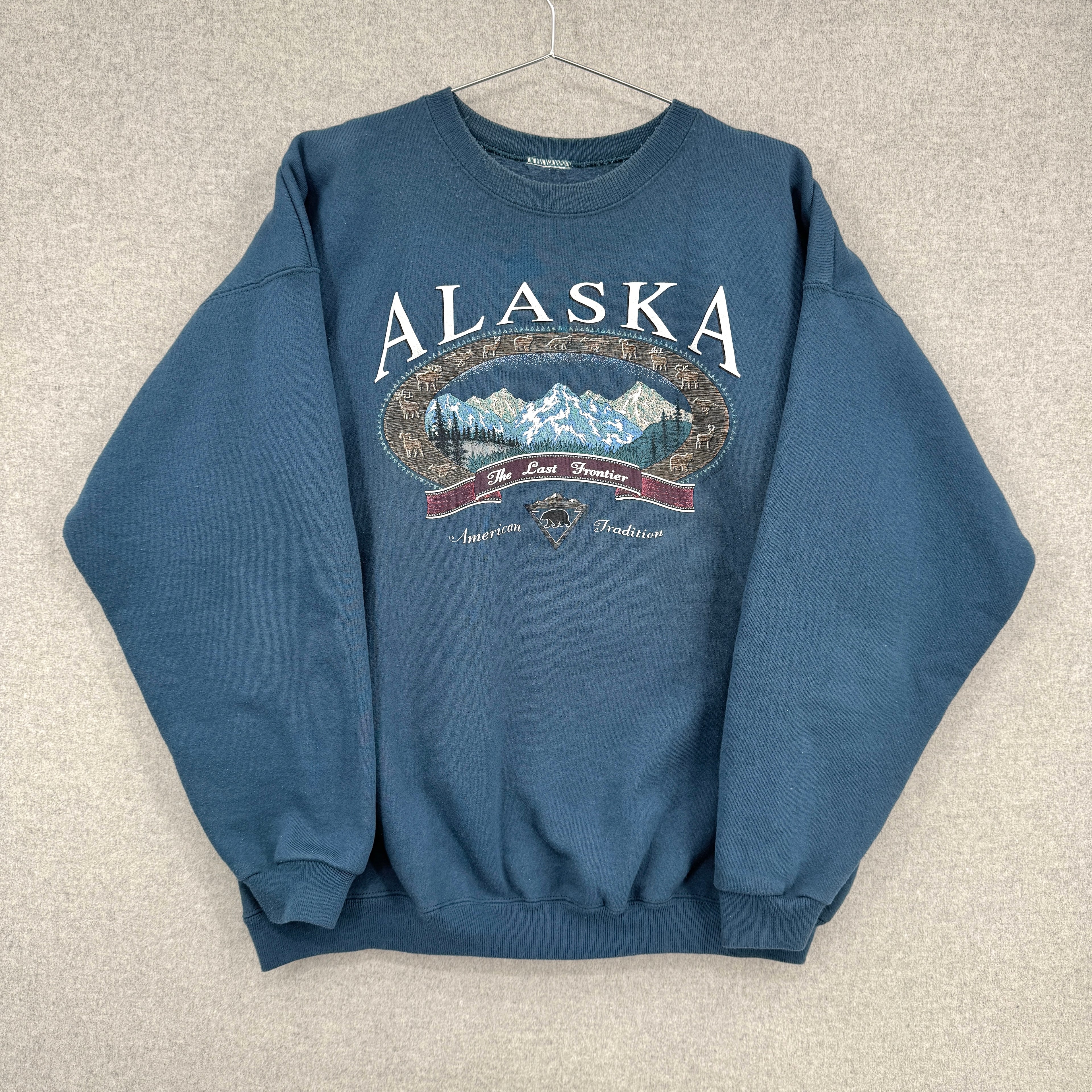 Blue sweatshirt with 'Alaska' and mountain graphic on a beige background