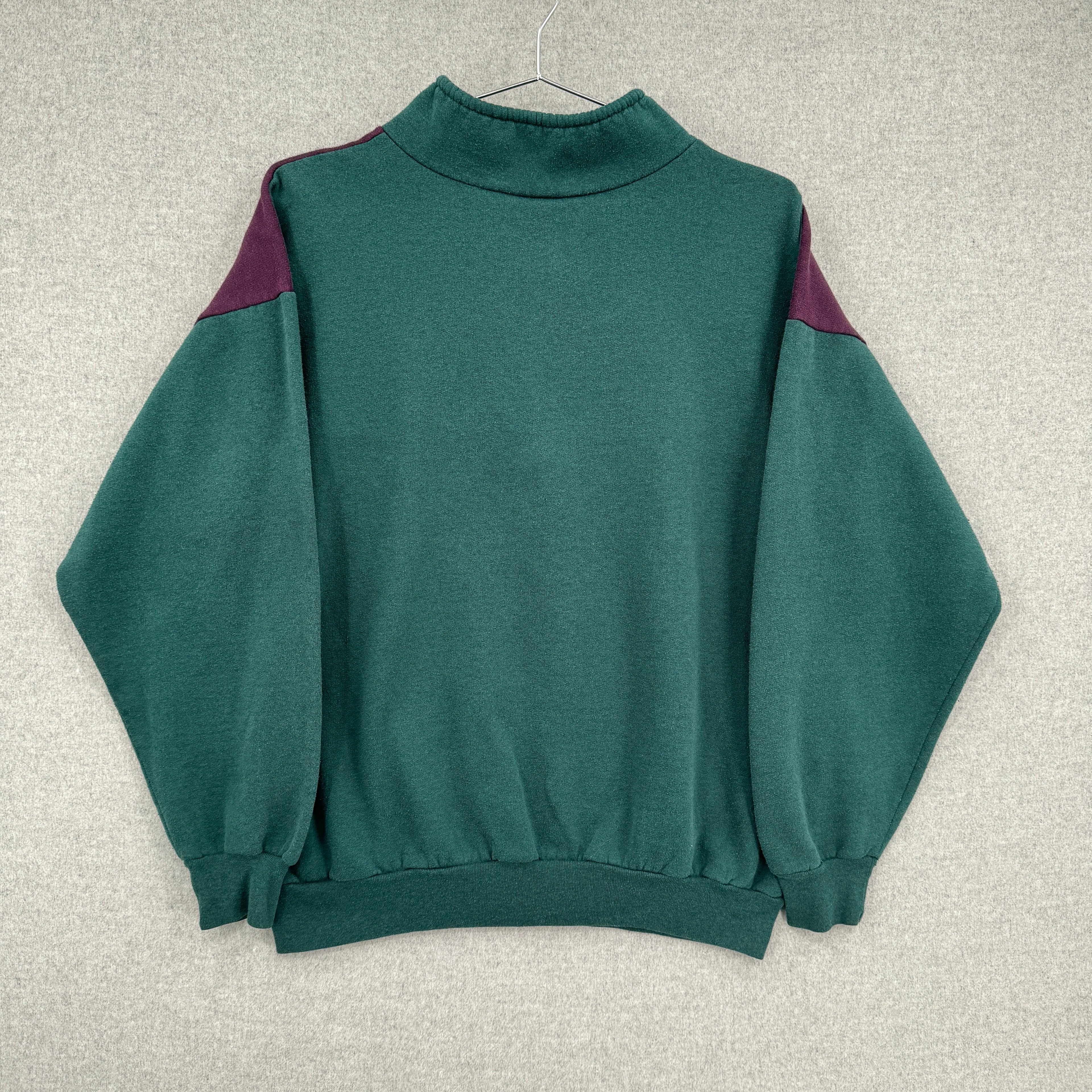 Green sweater with purple accents on a blank background.