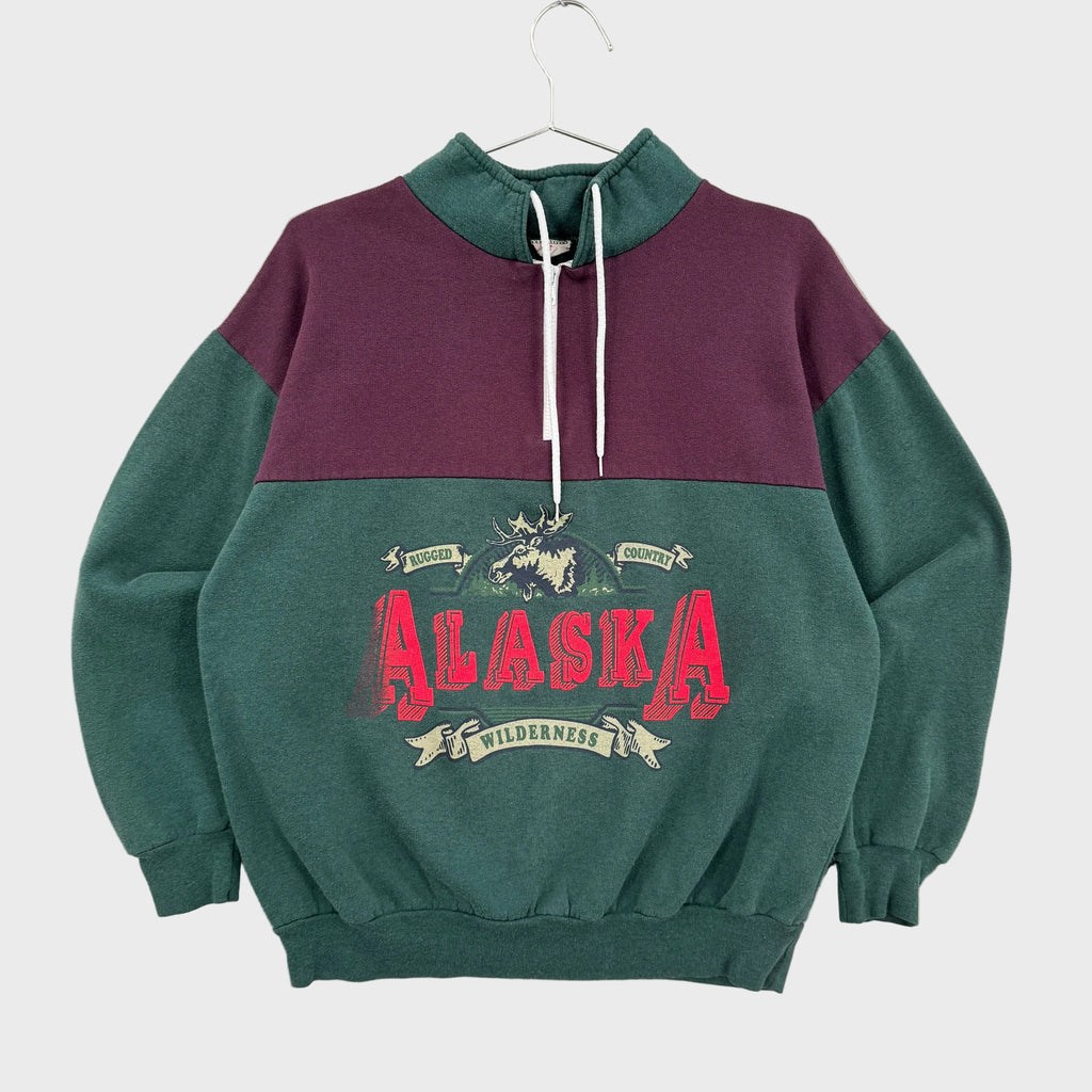 Green and purple sweatshirt with 'Alaska' graphic on a white surface