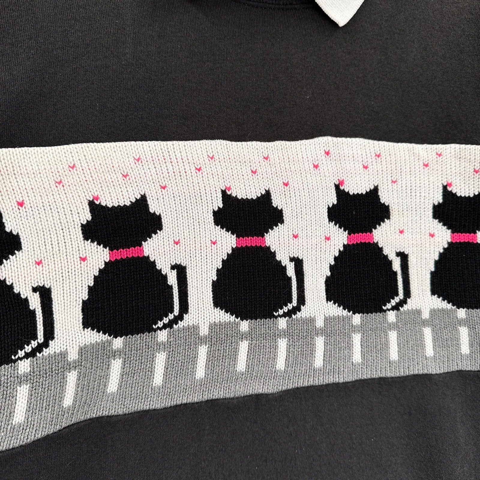 Black sweater with a pattern of black cats and pink bows on a gray background