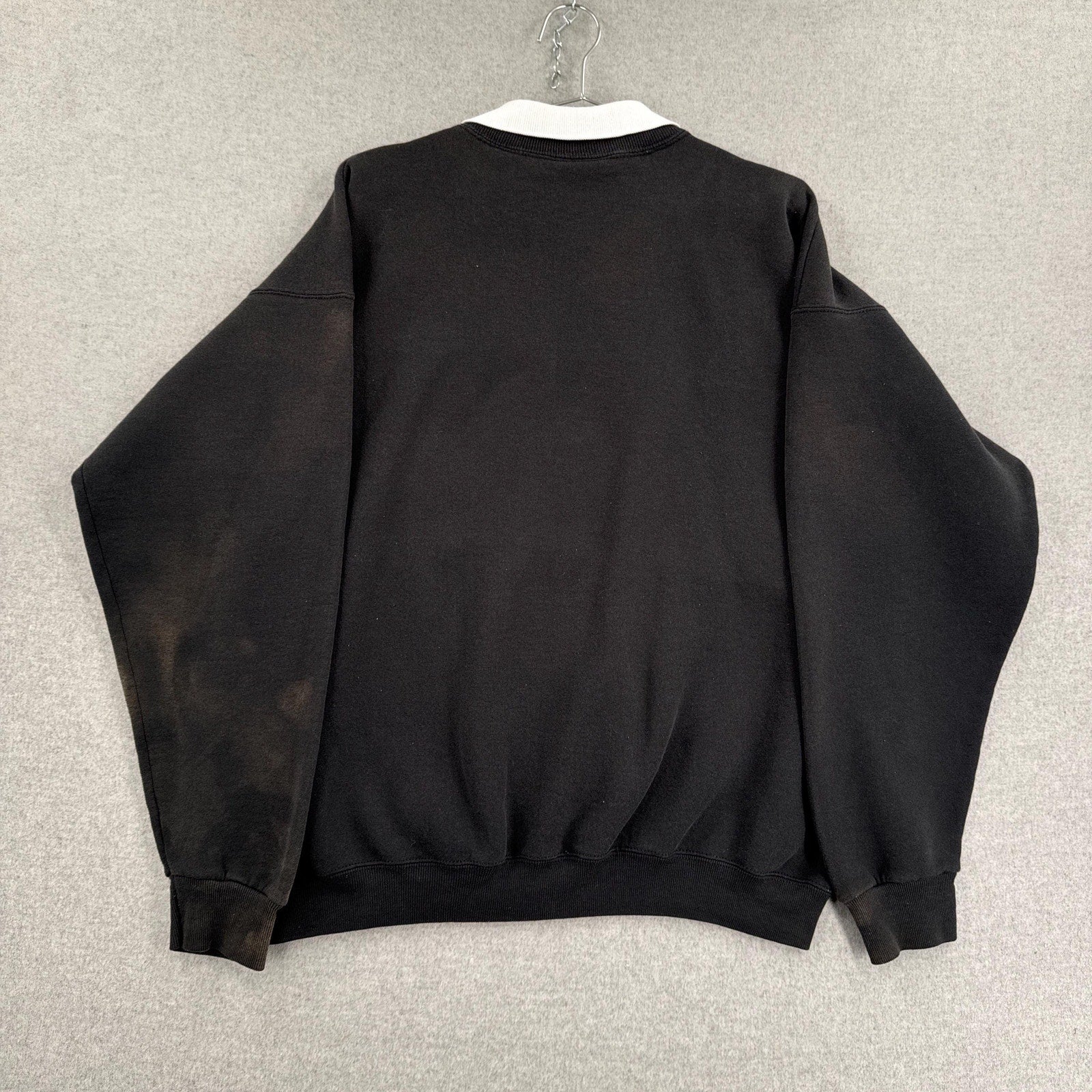 Black sweatshirt on a hanger against a neutral background