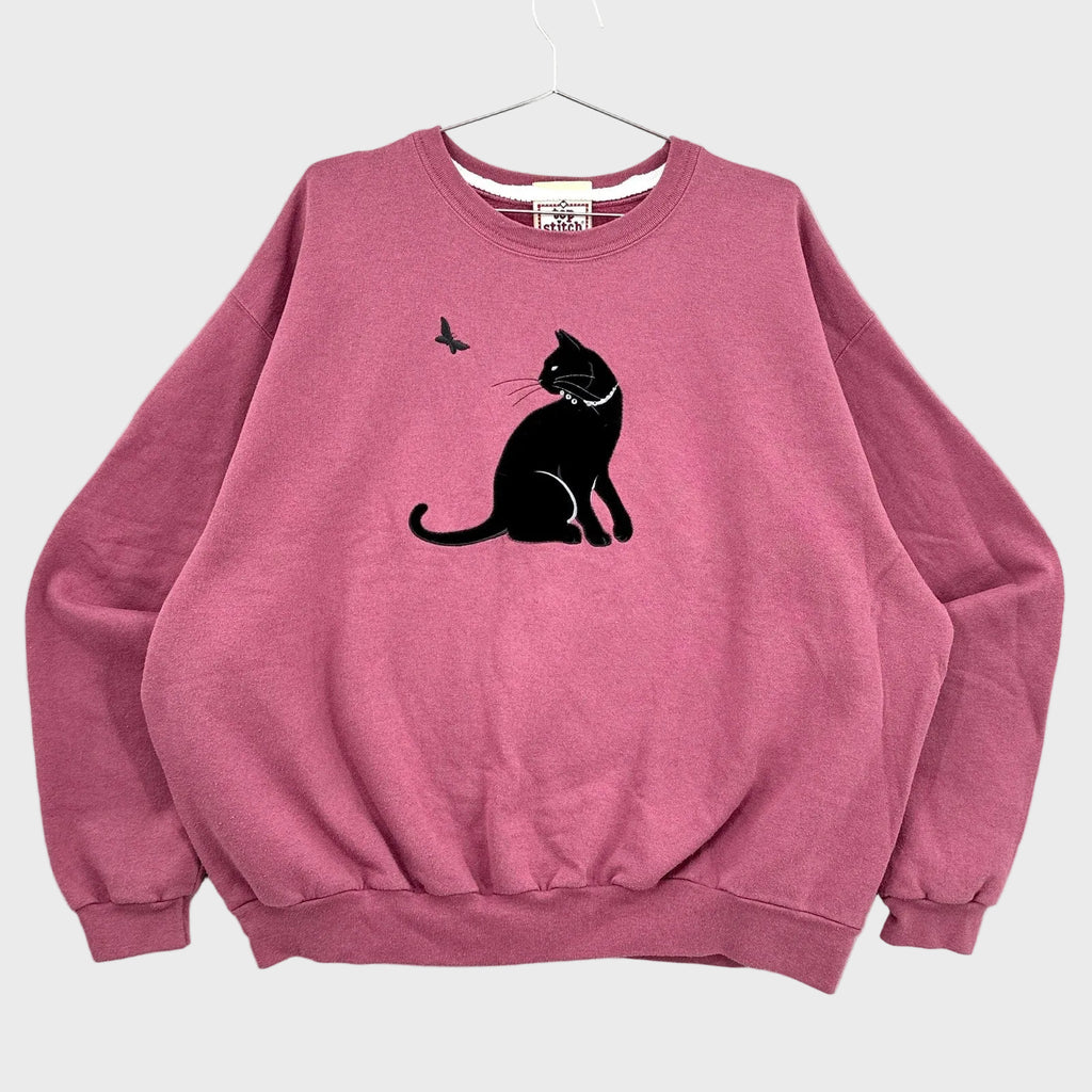 Pink sweatshirt with a black cat and butterfly design on a gray background
