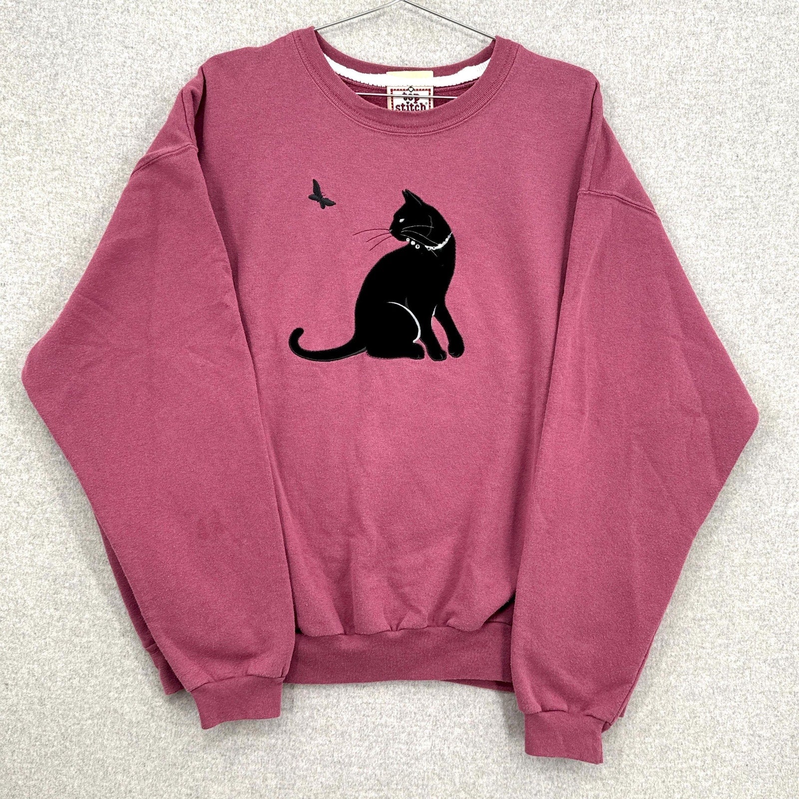 Pink sweatshirt with a black cat graphic on a light gray background