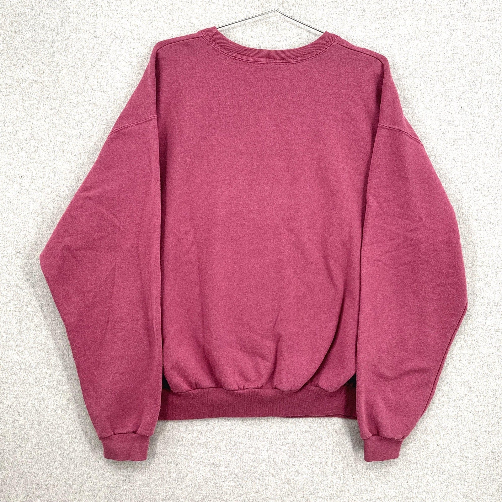 Pink sweatshirt on a hanger against a light gray background