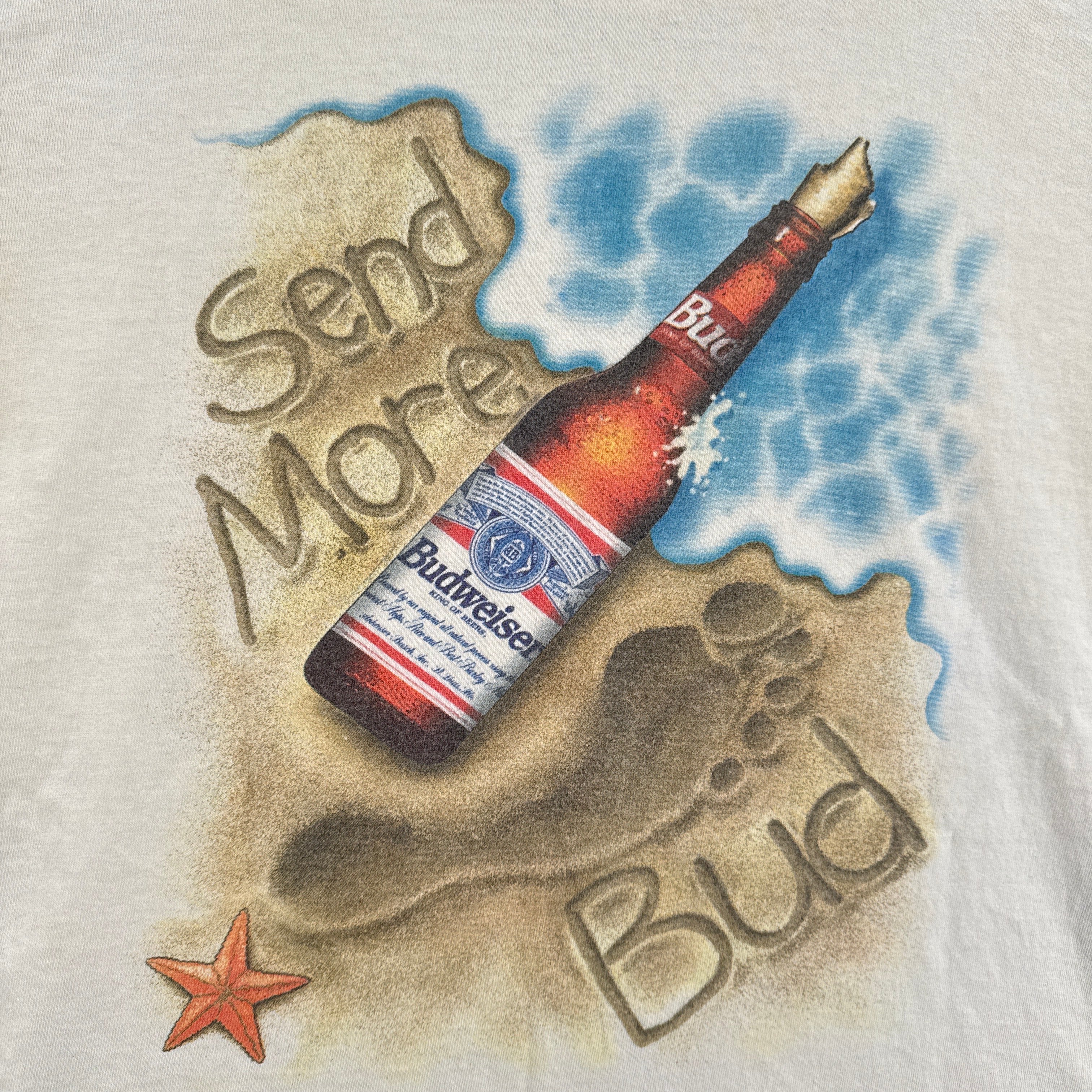 Budweiser bottle in sand with 'Save Me' text on a white background