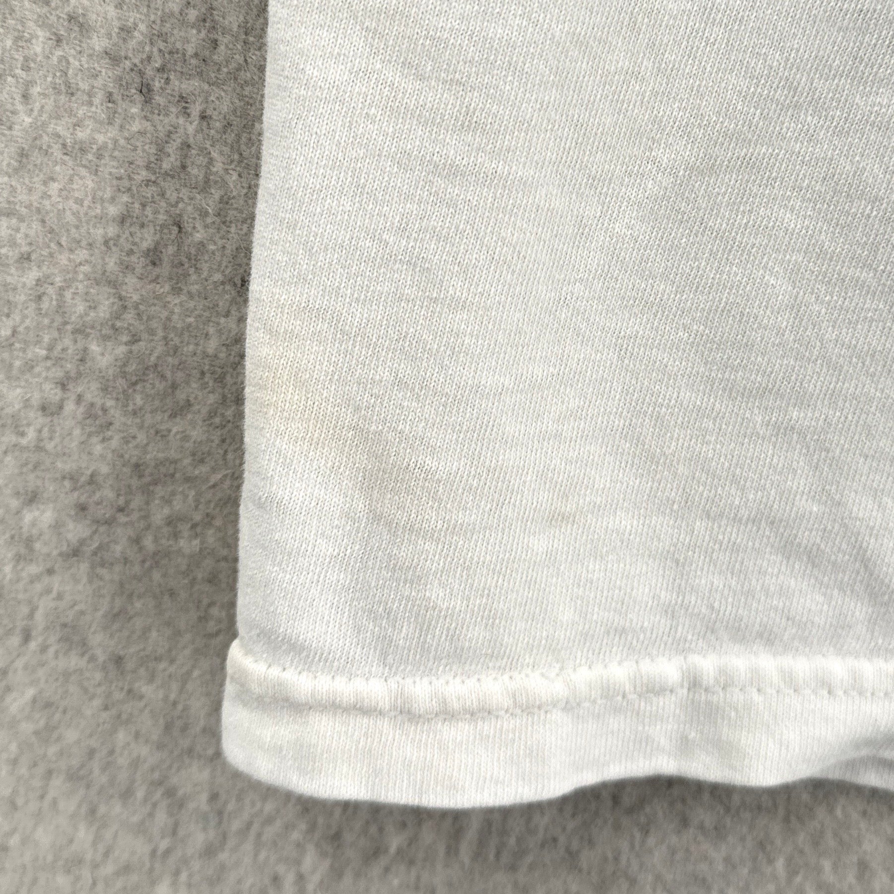 Close-up of a white fabric edge with a gray background, stain spots