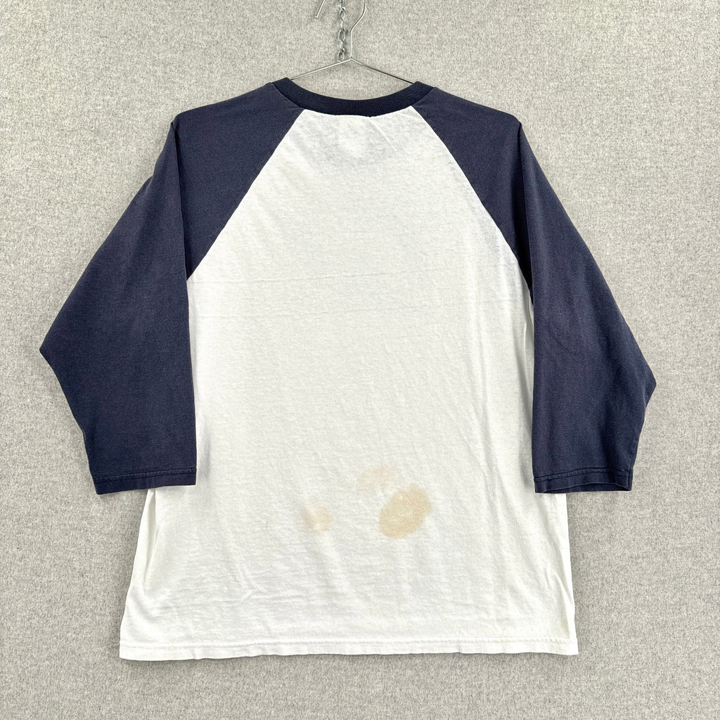 White baseball shirt with navy sleeves on a hanger against a neutral background