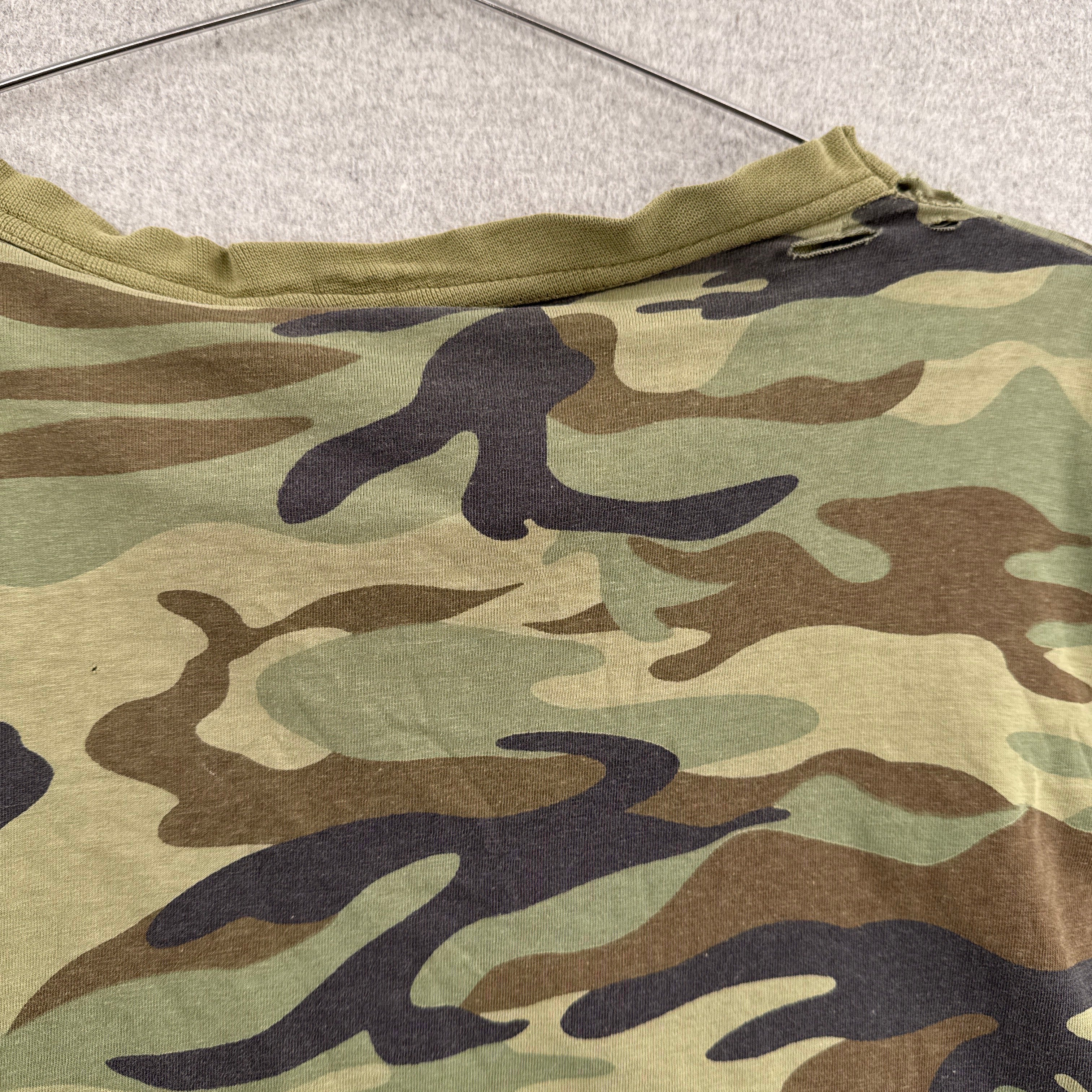 Camouflage-patterned fabric on a textured surface. back of collar with holes