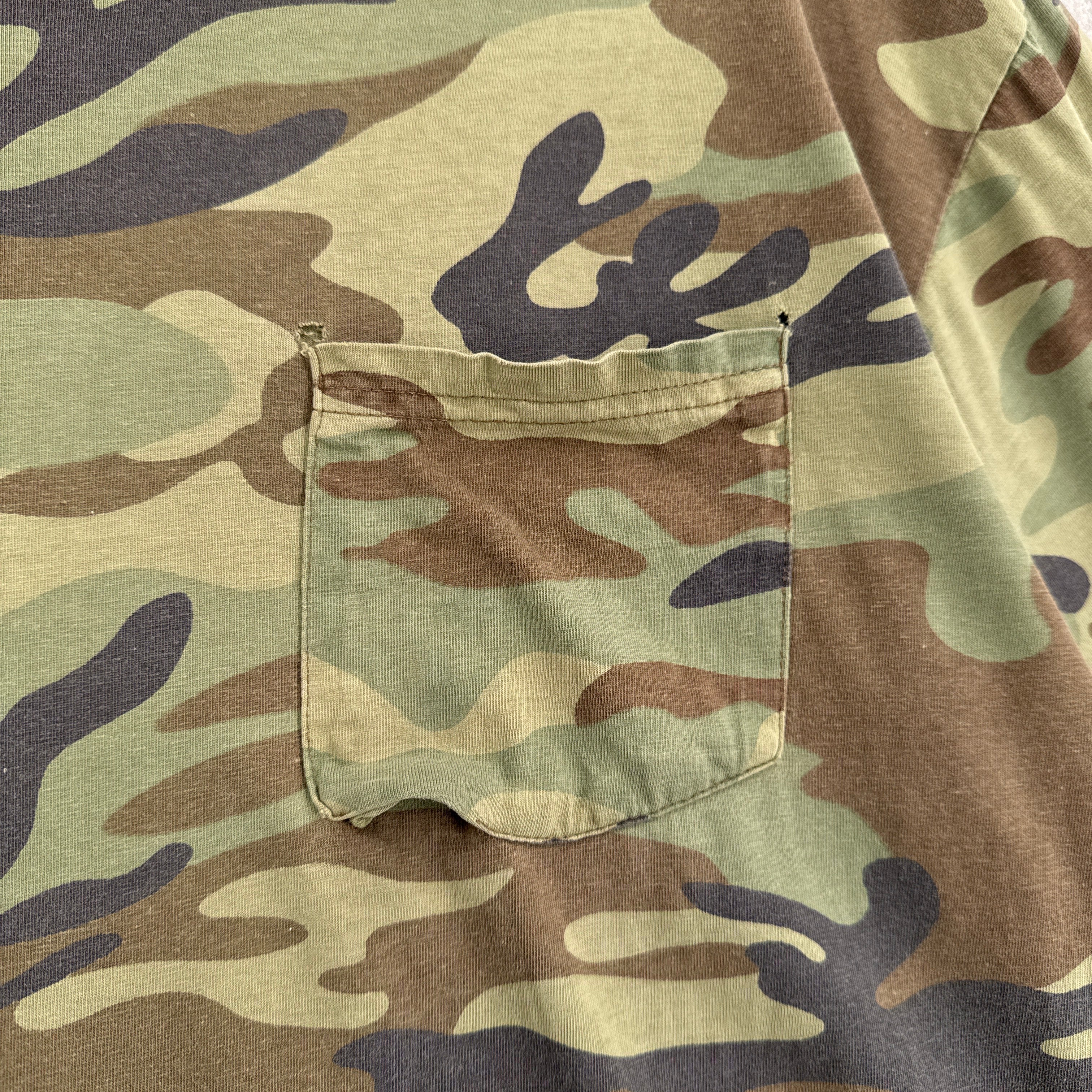 Close-up of a camouflage pattern on fabric. Front pocket with holes