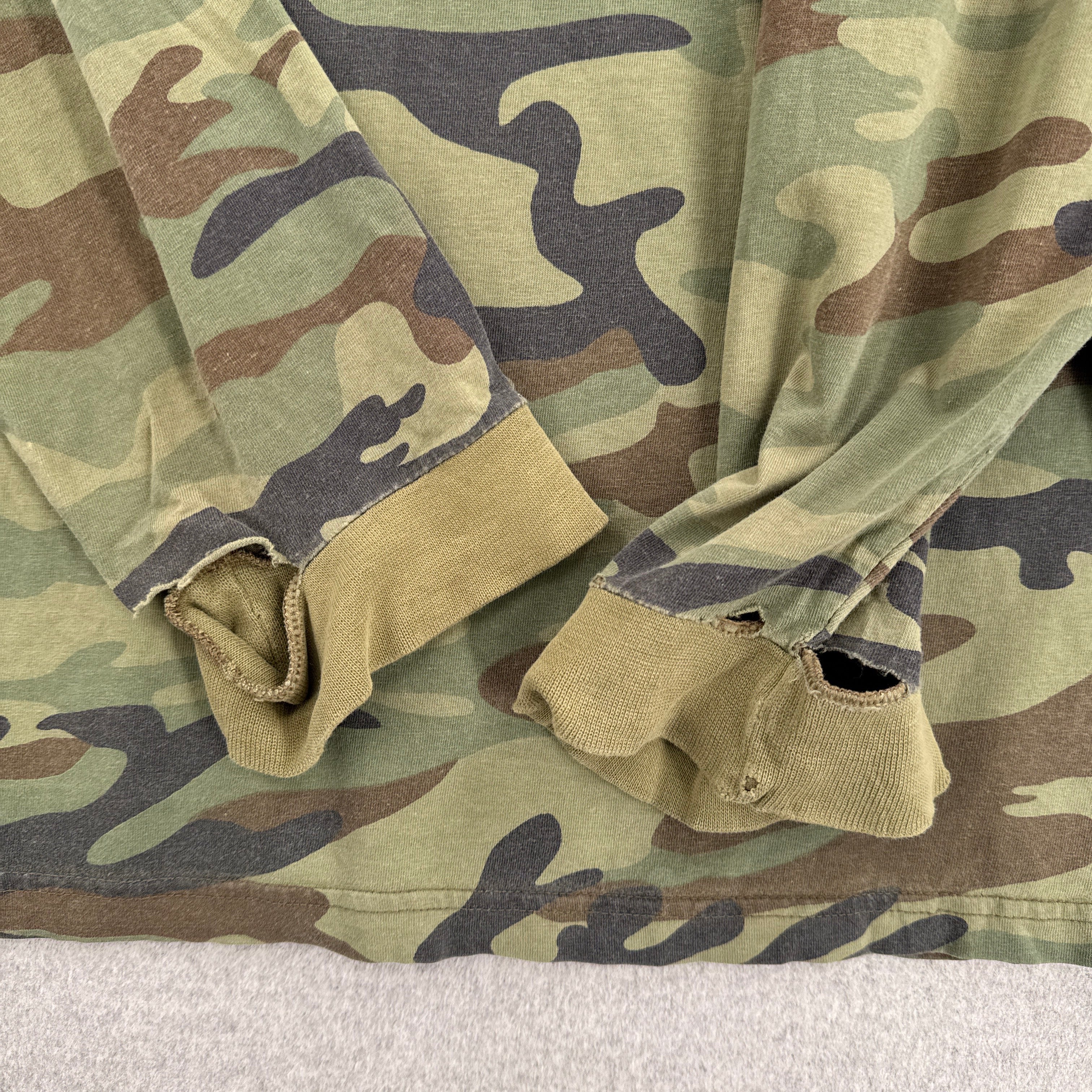 Close-up of camouflage fabric with a neutral background. Sleeves with major holes