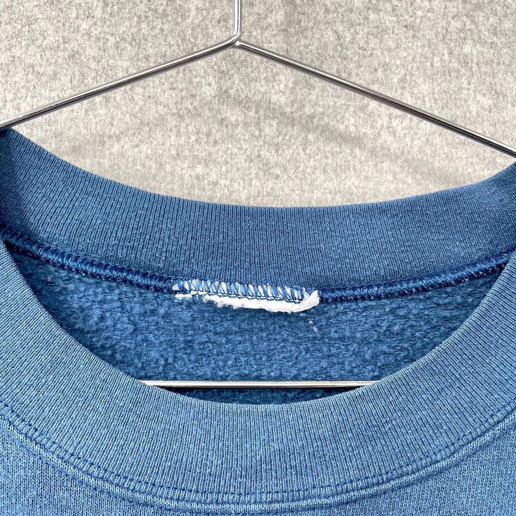 Blue shirt on a hanger with a visible tear.