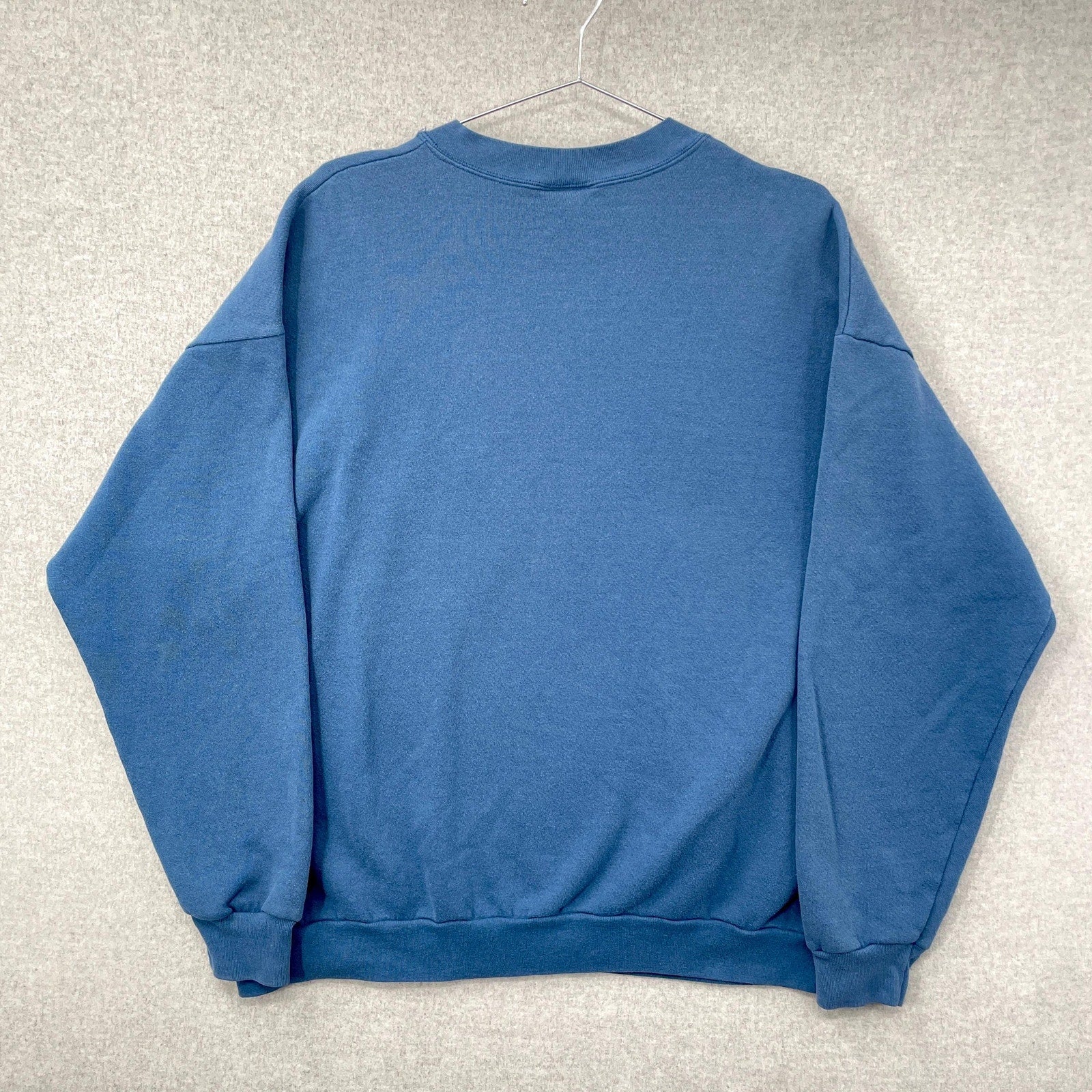 Blue sweatshirt on a hanger against a gray textured background