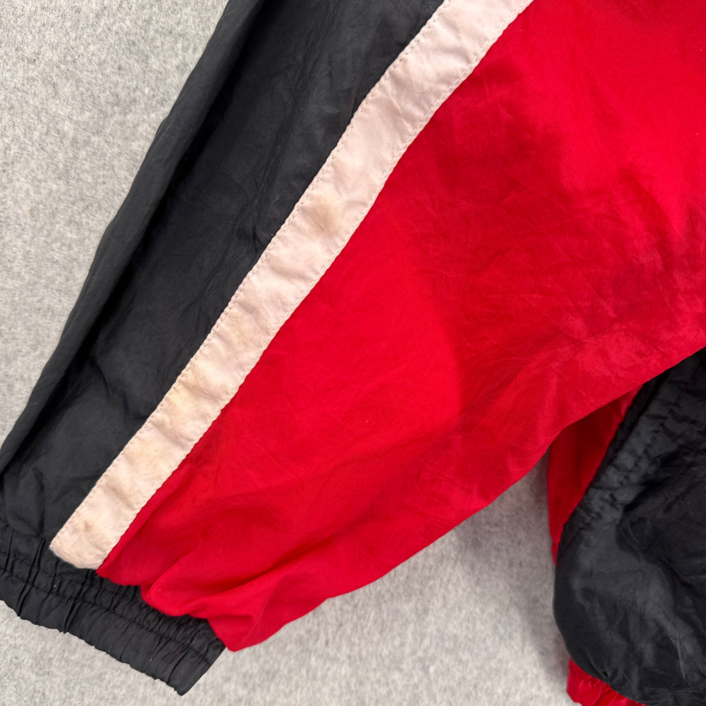 Close-up of a red and black jacket with beige lining on a gray surface. discolouration on white area