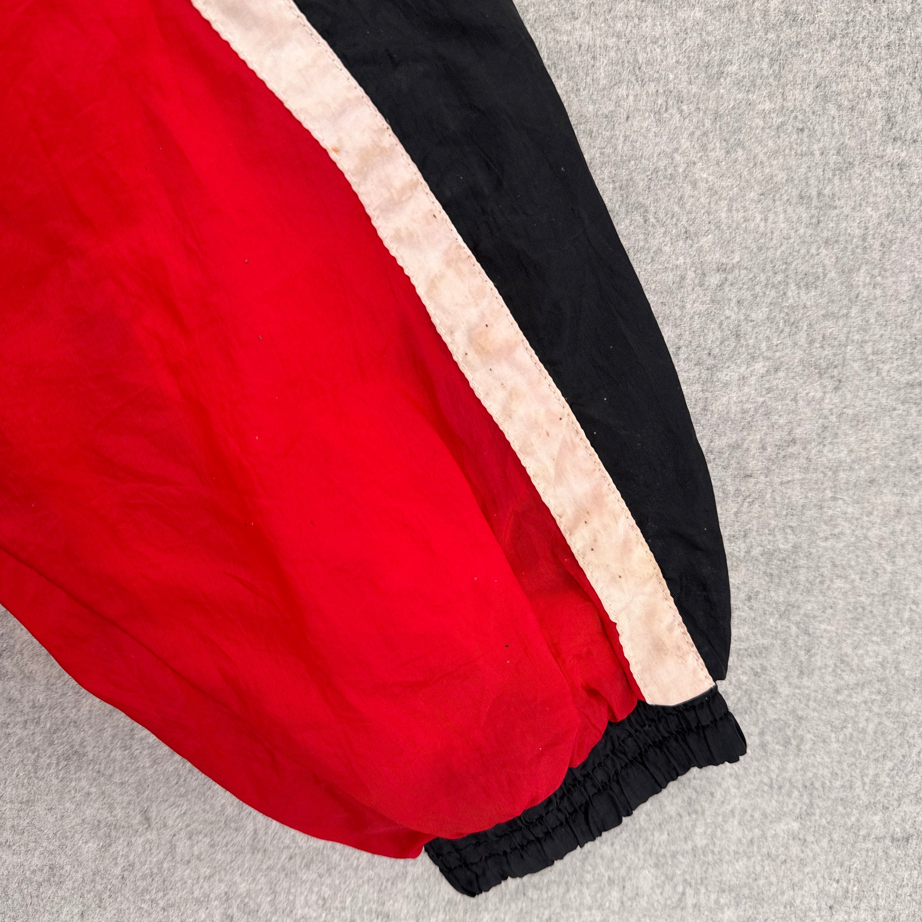 Red pants with black and beige stripes on a gray background. discolouration on white fabric