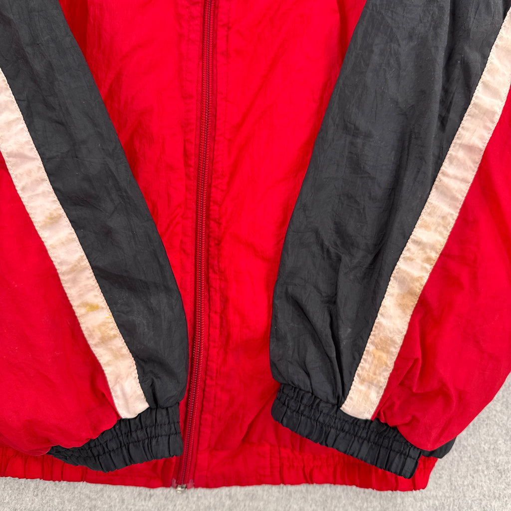Red jacket with black and beige accents on a neutral background. discolouration stain on white fabric