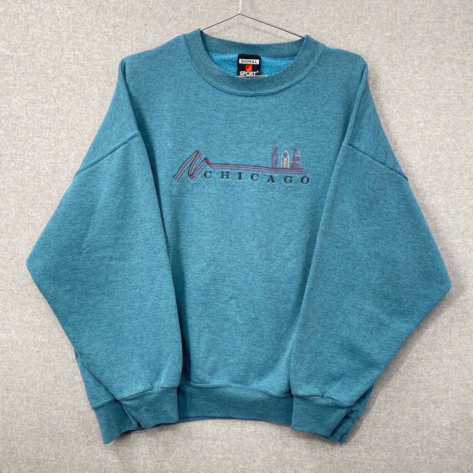 Blue sweatshirt with 'Chicago' skyline design on a gray background