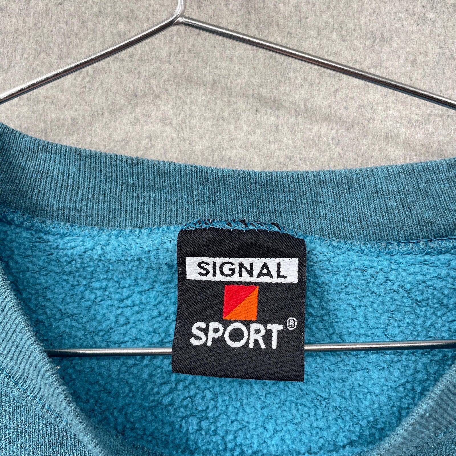 Blue fleece garment with Signal Sport label on a hanger