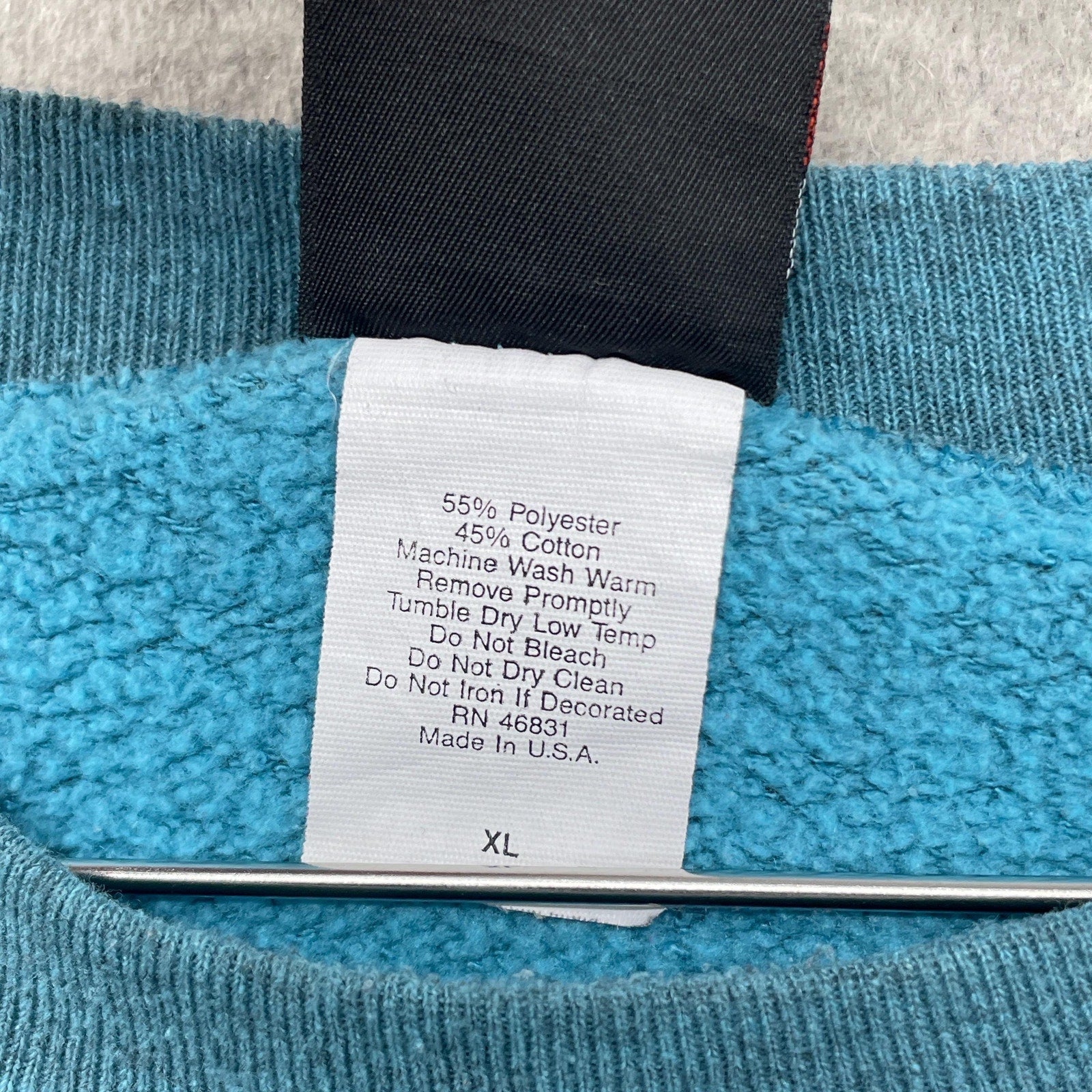 Clothing label on a blue garment with text details size XL