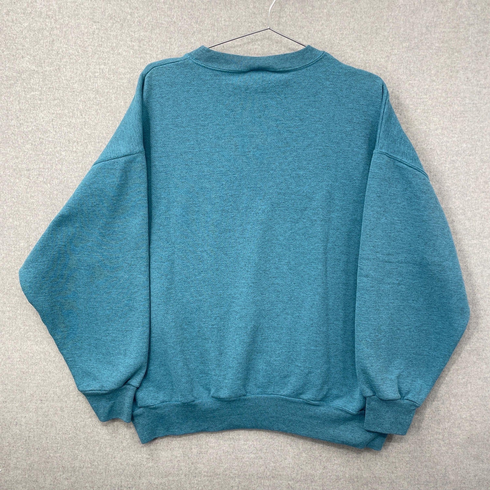 Blue sweatshirt on a hanger against a gray background