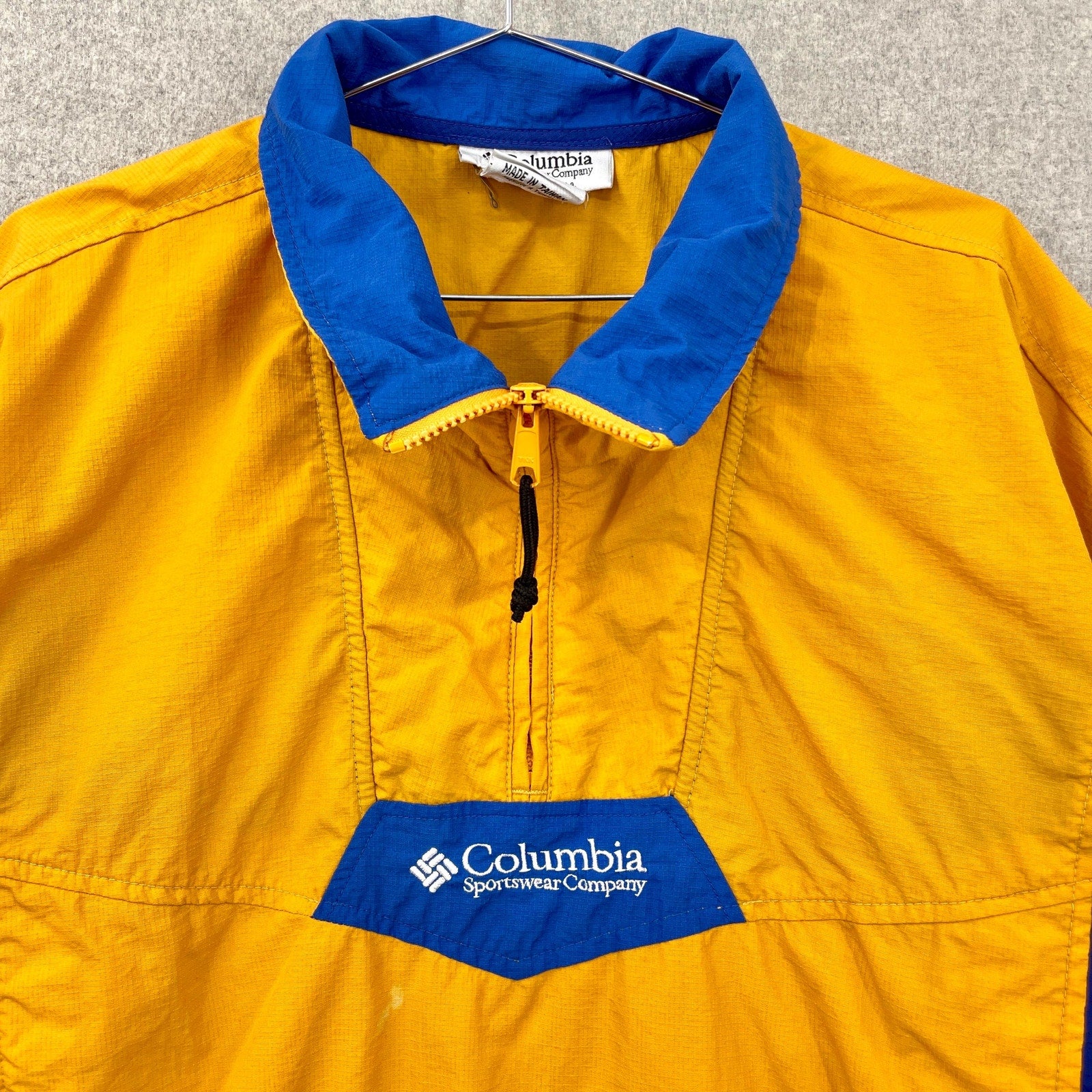 Yellow jacket with blue collar and Columbia Sportswear Company logo on a gray background