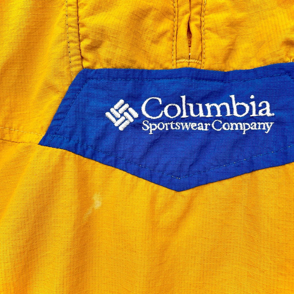 Close-up of Columbia Sportswear Company logo on a yellow garment. small stain spot near front logo