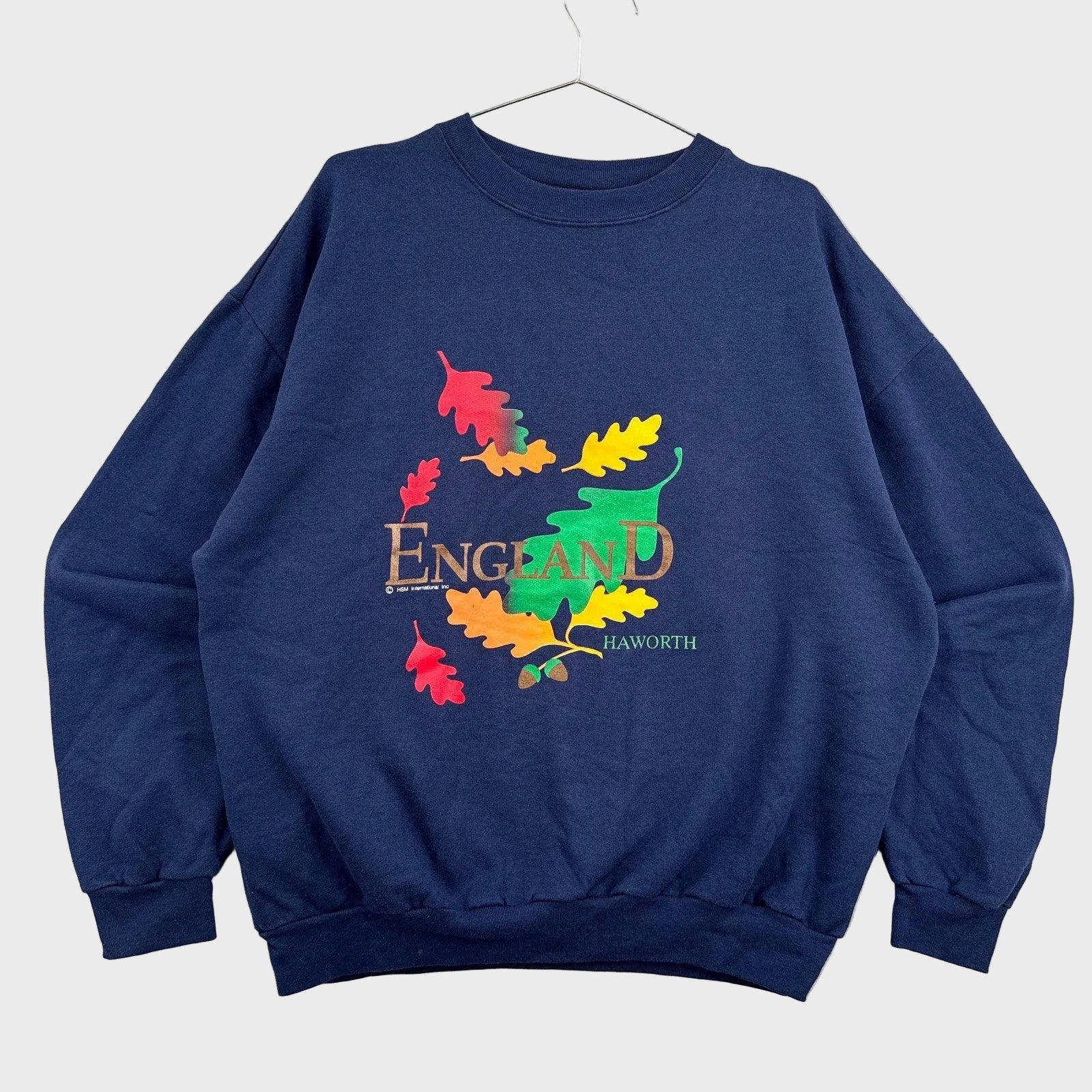 Navy blue sweatshirt with colorful 'England' design on a textured gray background