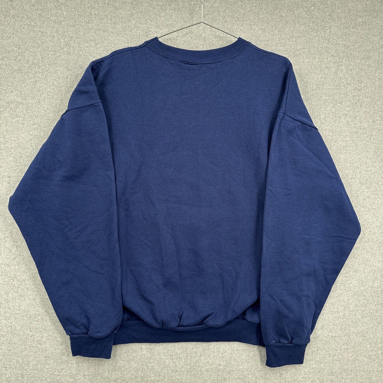 Blue sweatshirt on a hanger against a neutral background