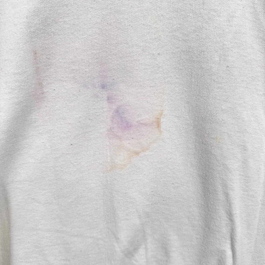 Close-up of a white fabric with a small colorful stain.