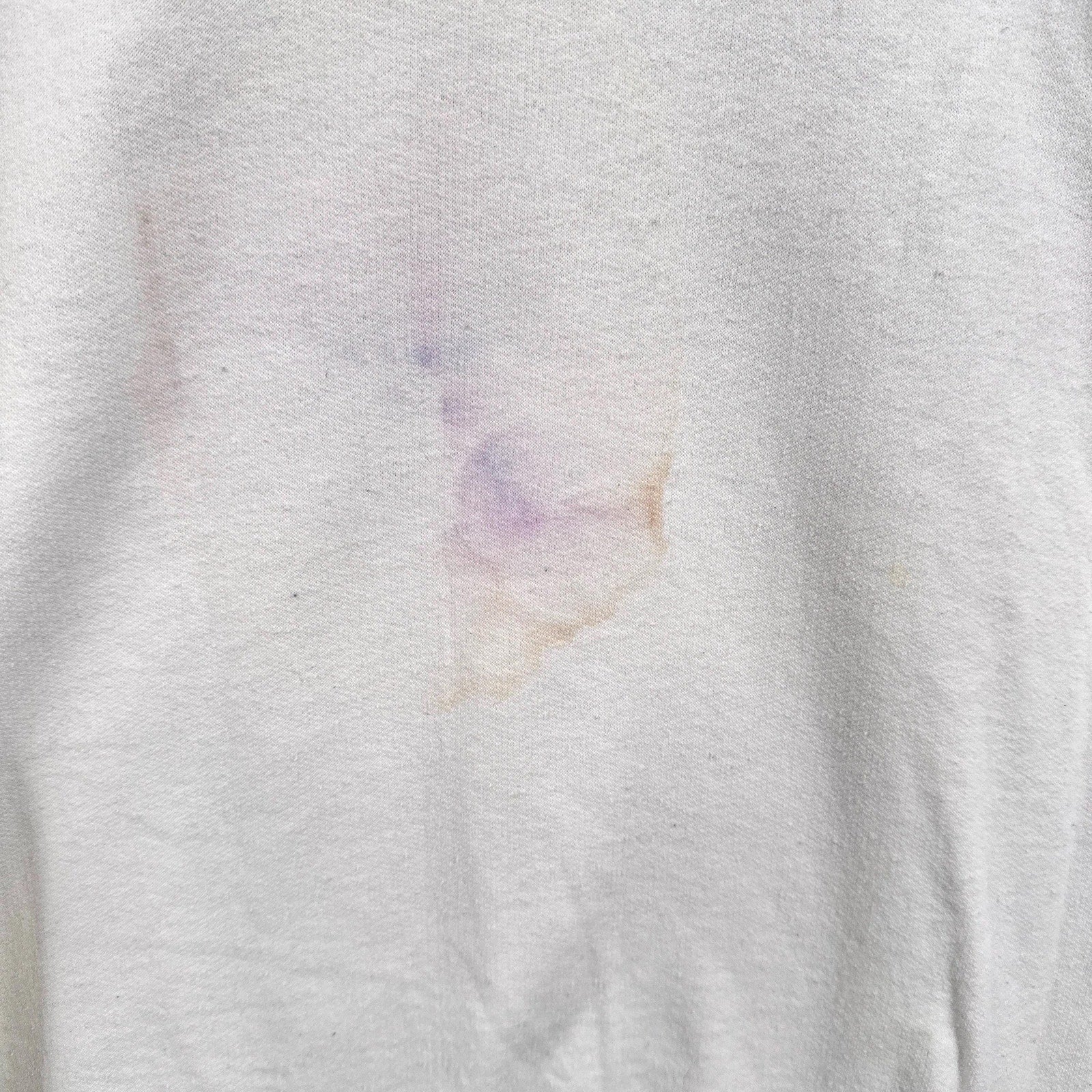 Close-up of a white fabric with a small colorful stain.