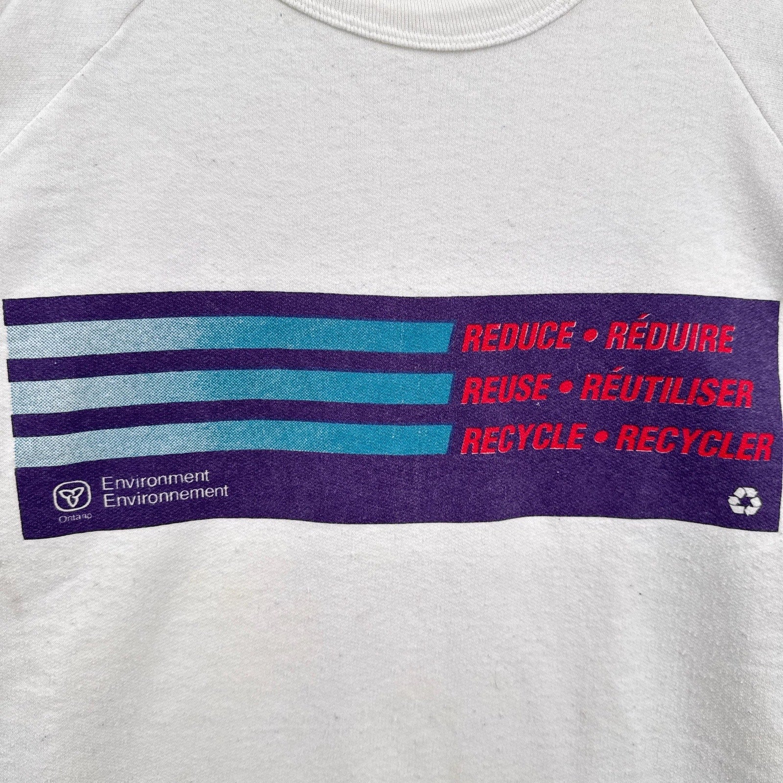 Gray sweatshirt with a recycling message in English and French on a purple stripe.