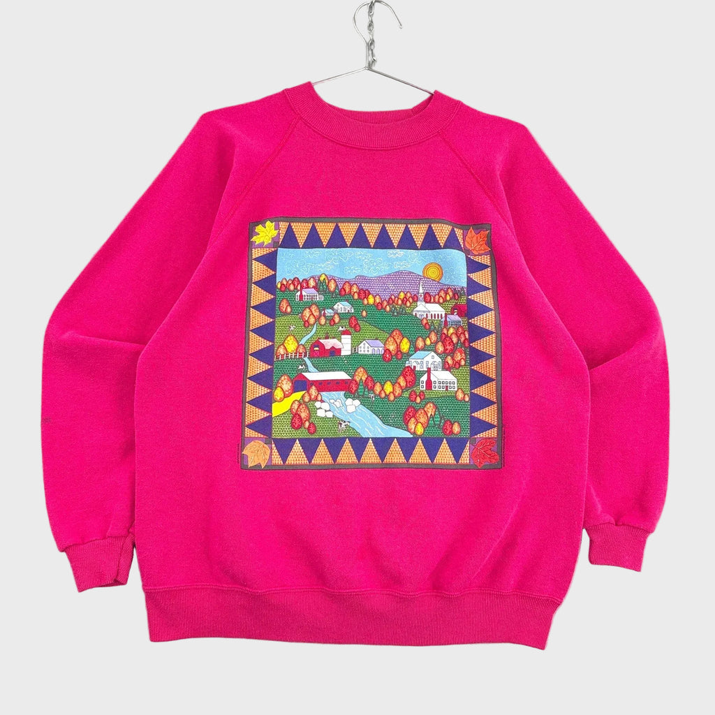Pink sweatshirt with a colorful patchwork design on a gray background