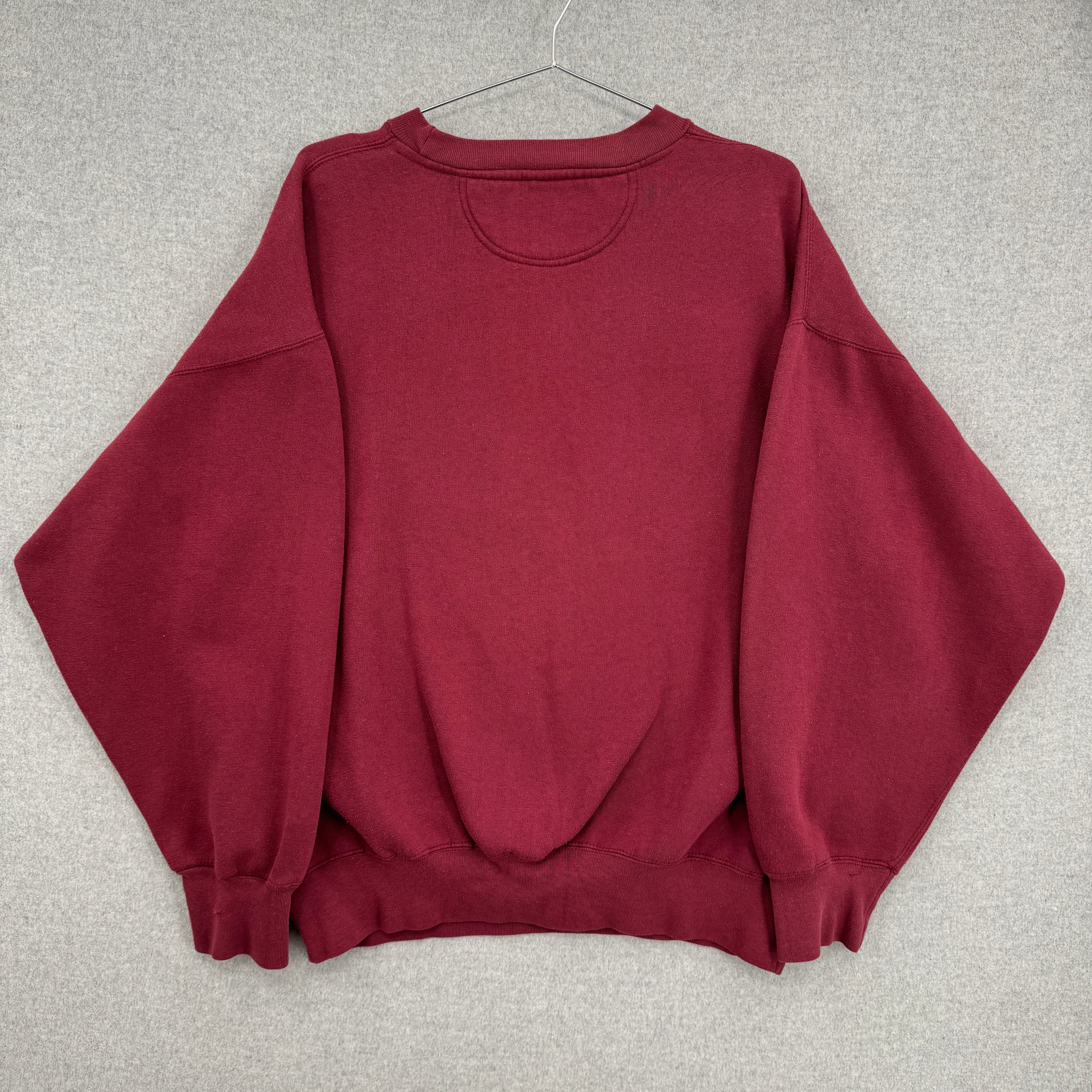 Maroon sweatshirt on a hanger against a gray background