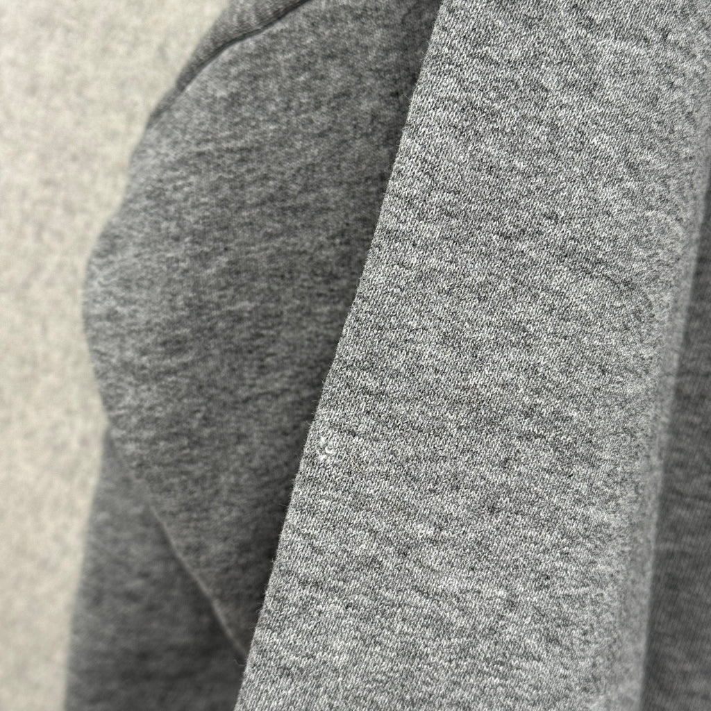 Close-up of gray fabric texture on a neutral background, small hole spot