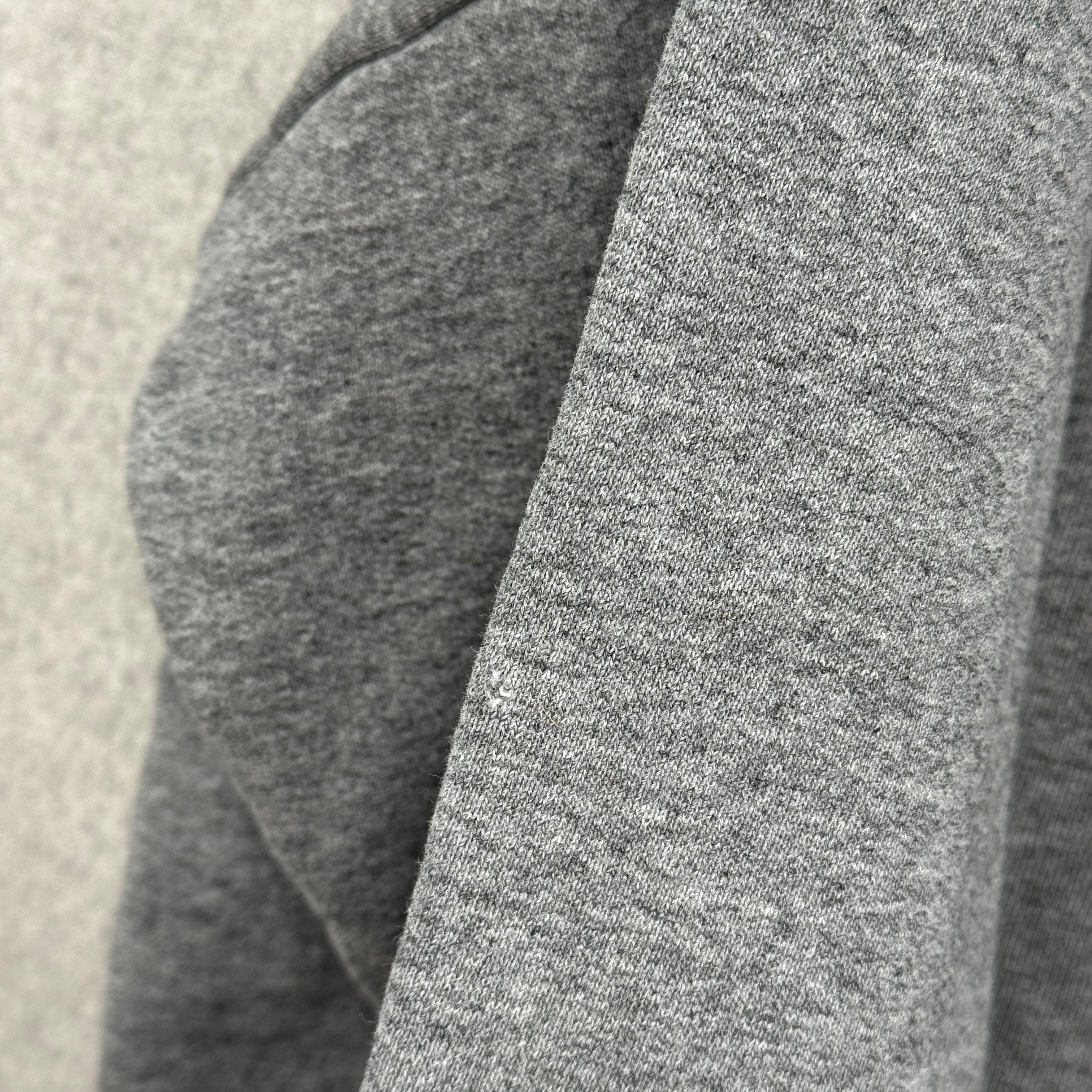 Close-up of gray fabric texture on a neutral background, small hole spot
