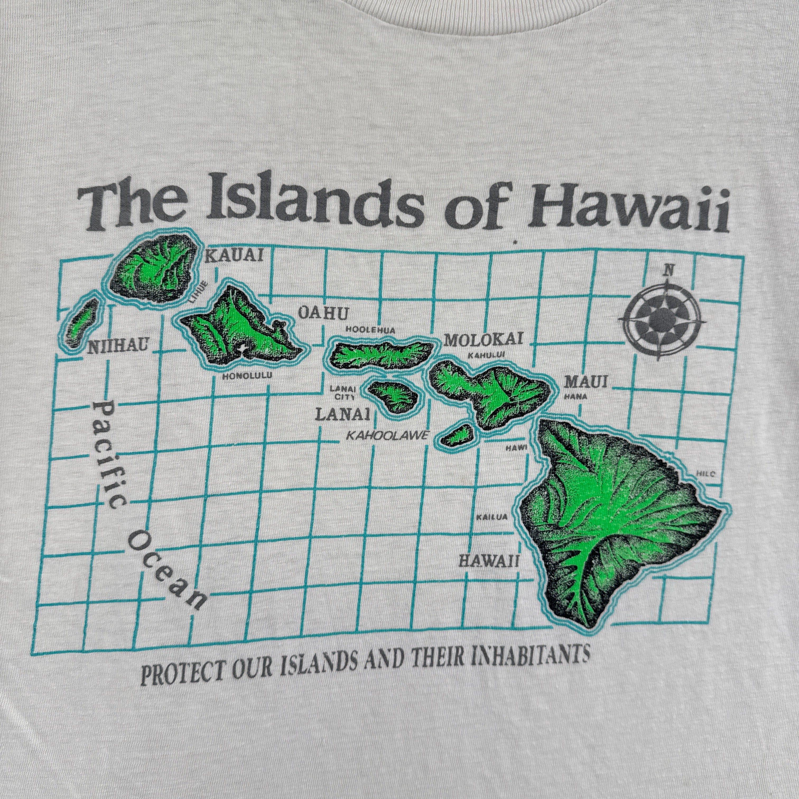 White t-shirt with a map of Hawaii in green and black text on a white background