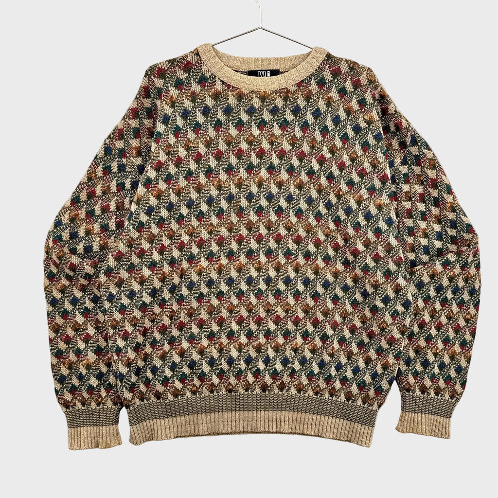Multicolored patterned sweater on a hanger against a neutral background