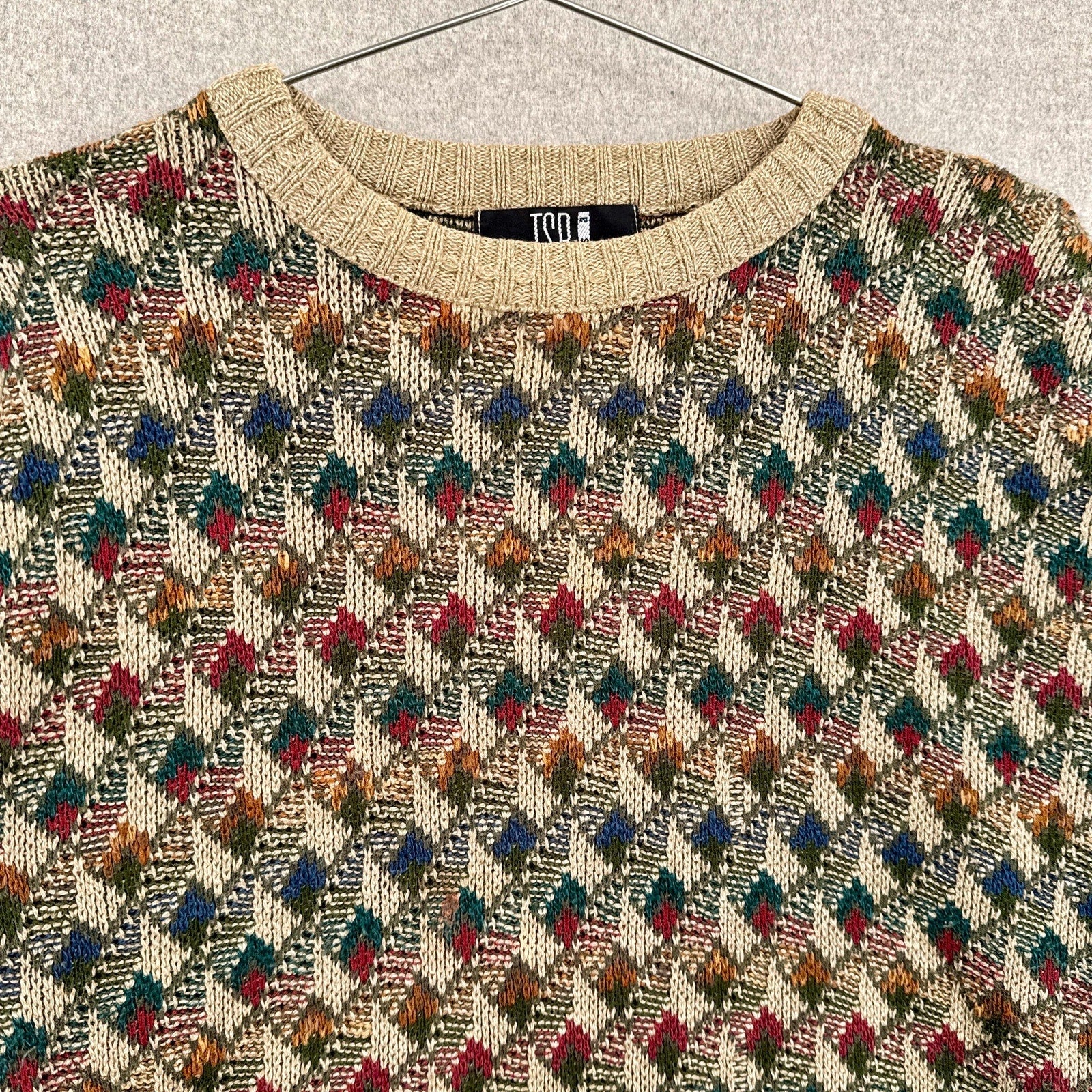 Patterned sweater with a visible brand label on a neutral background