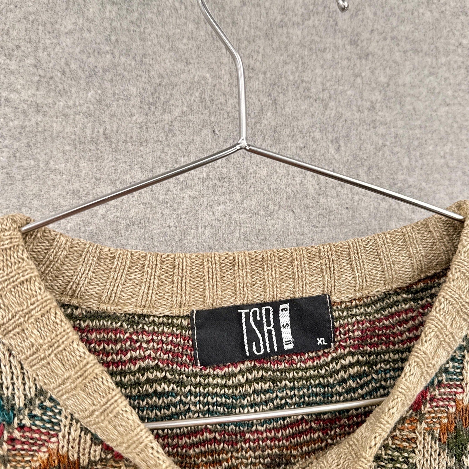 Textured sweater with a visible 'TSA' label on a hanger against a neutral background size XL