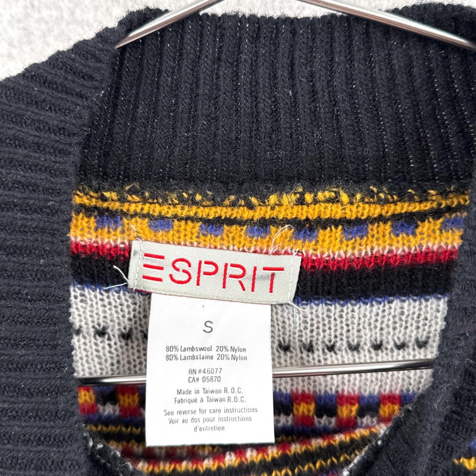 Black sweater with colorful pattern and Esprit label on a hanger. size small