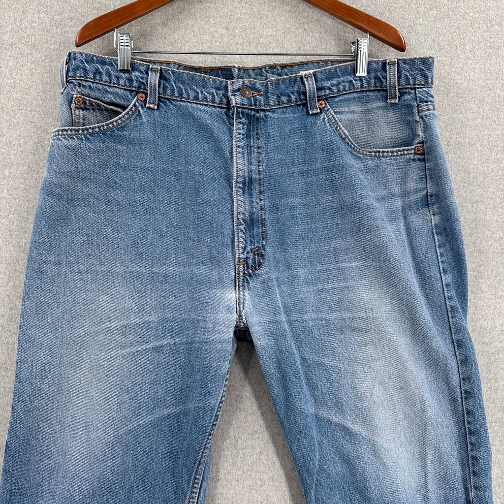 Blue jeans on a hanger against a gray background
