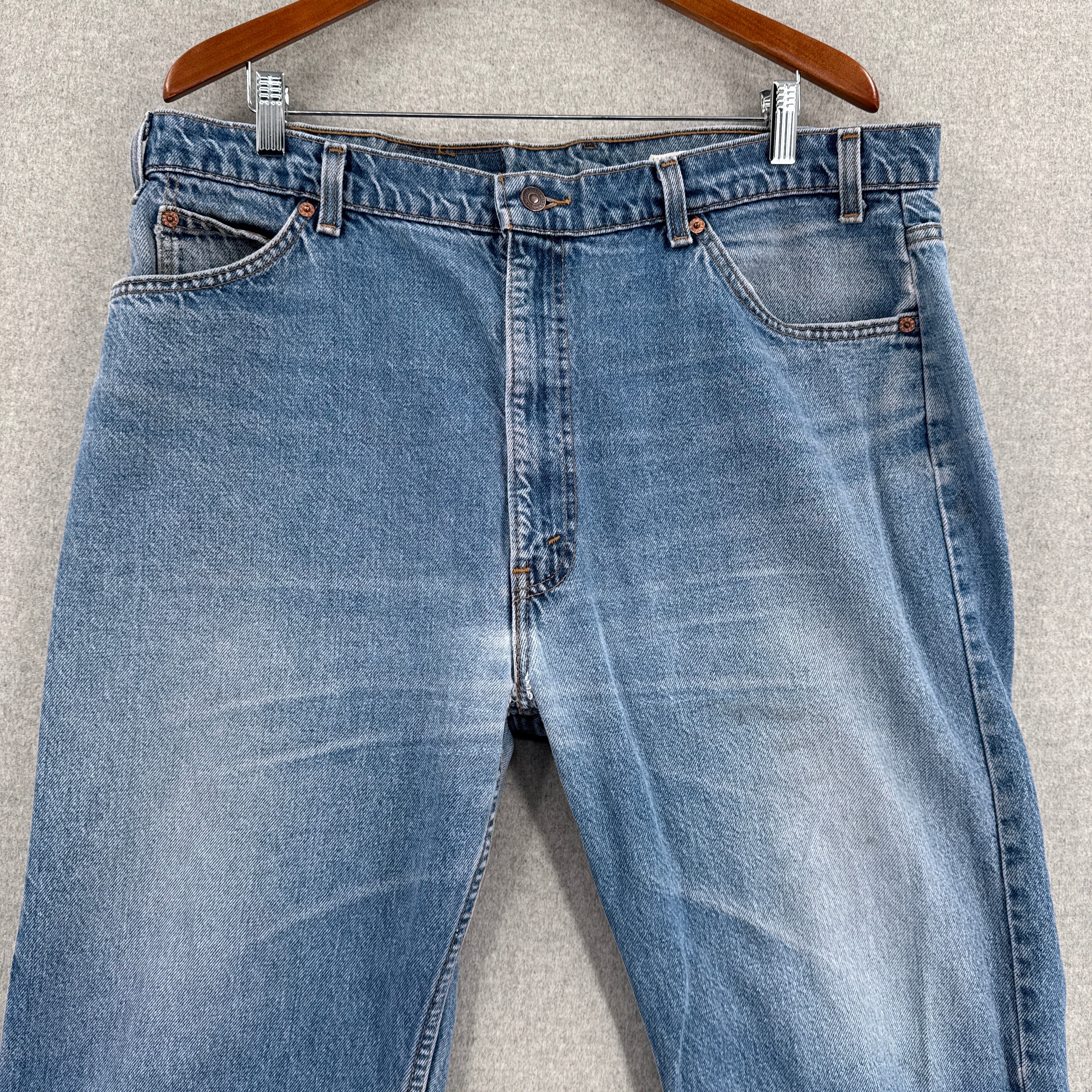 Blue jeans on a hanger against a gray background