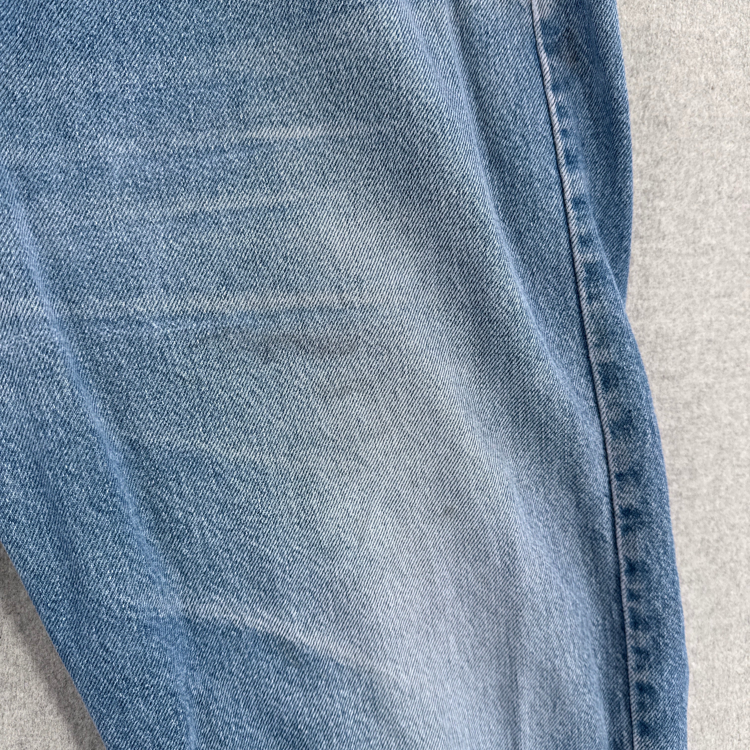 Close-up of blue denim fabric on a gray background, faint stain spots