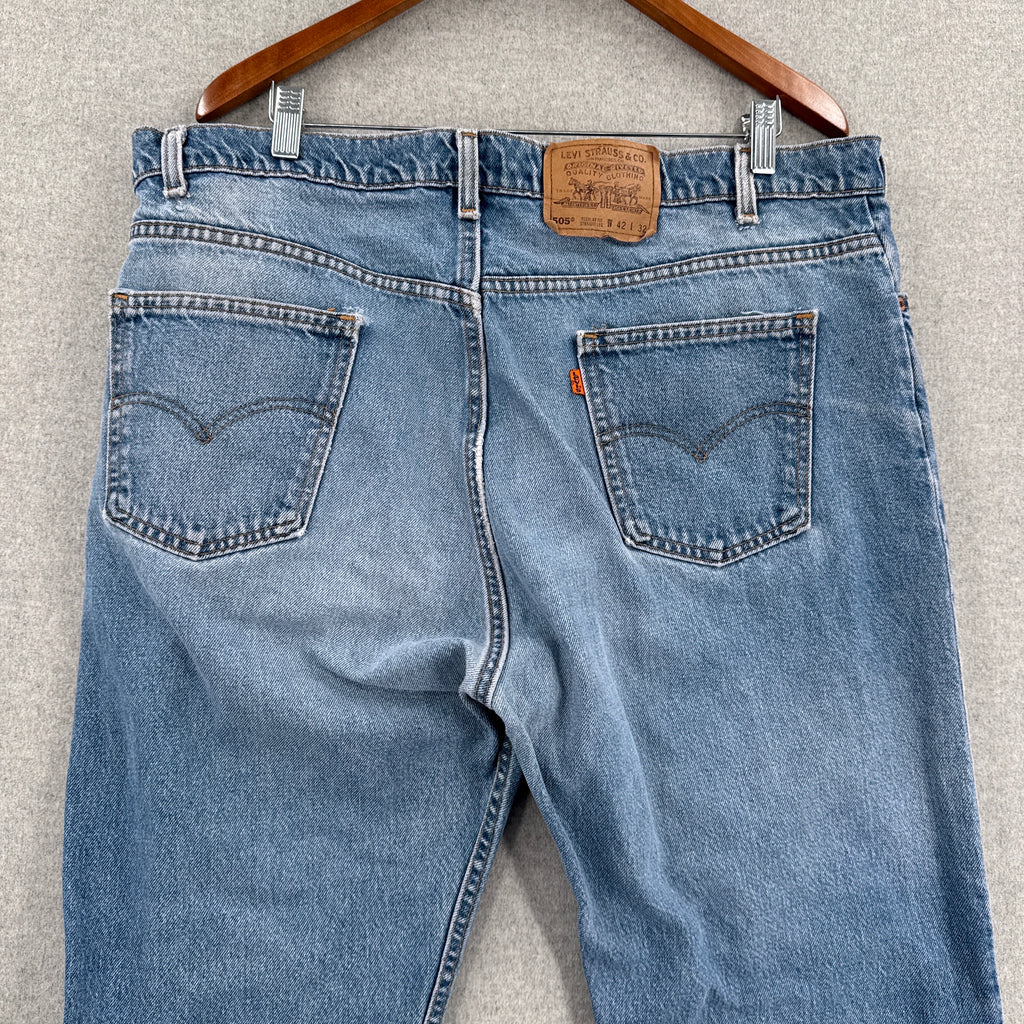 Pair of blue jeans with a belt on a gray surface