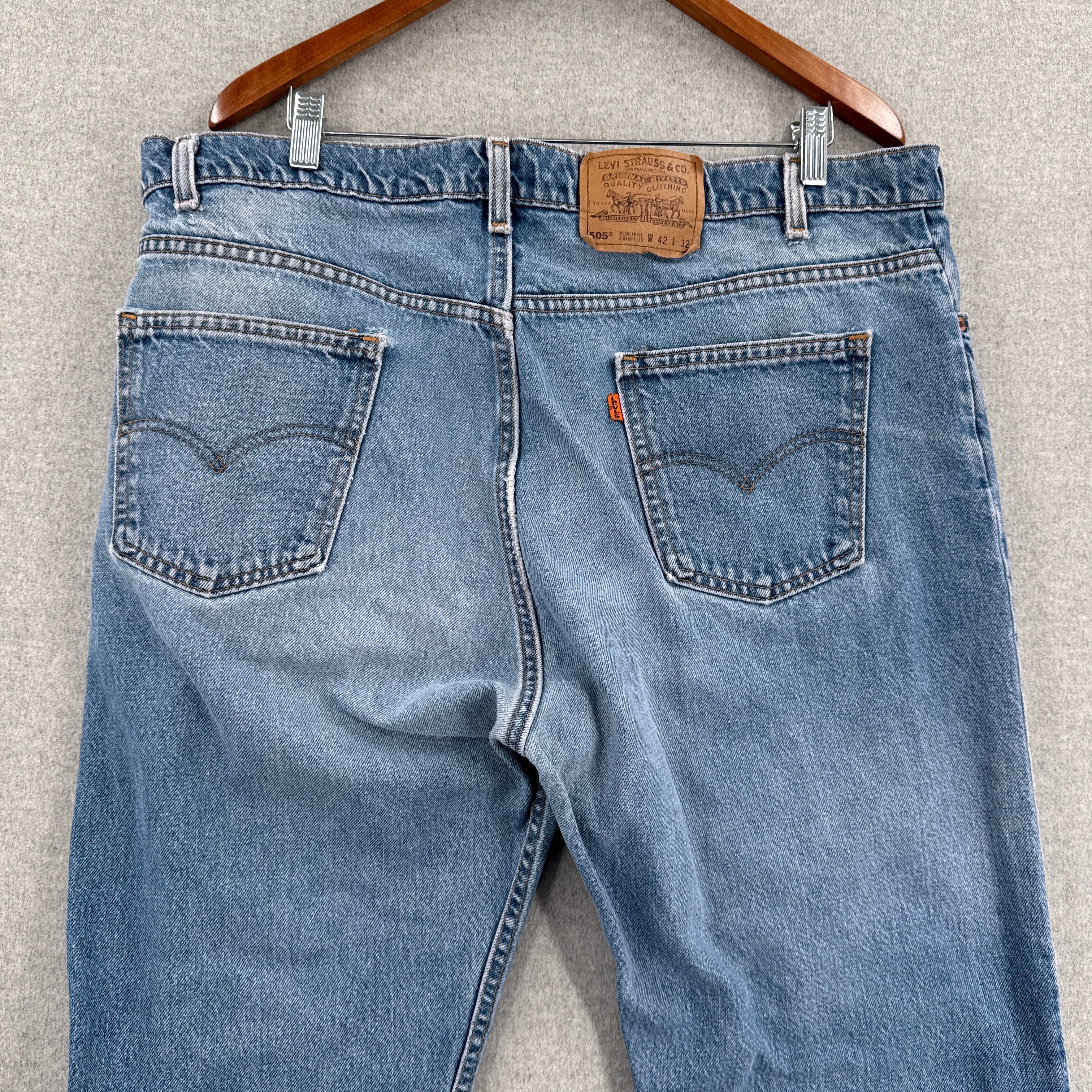 Pair of blue jeans with a belt on a gray surface